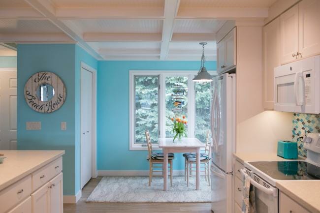 Light blue back wall accenting a white cabinet detailed kitchen, designed by Silver Leaf Interiors.
