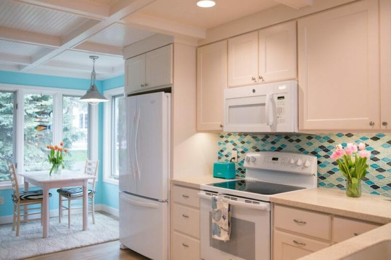 White cabinet featured kitchen with a blue back wall accent, designed by Silver Leaf Interiors.