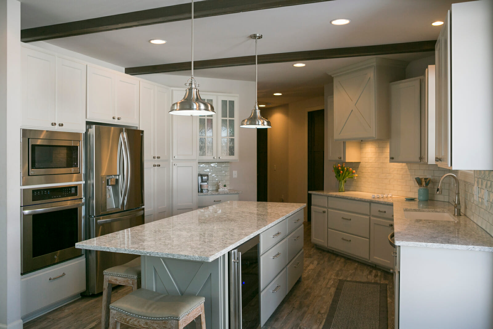 Modern kitchen featuring white cabinetry, stainless steel appliances, a large island with granite countertop, and pendant lighting.