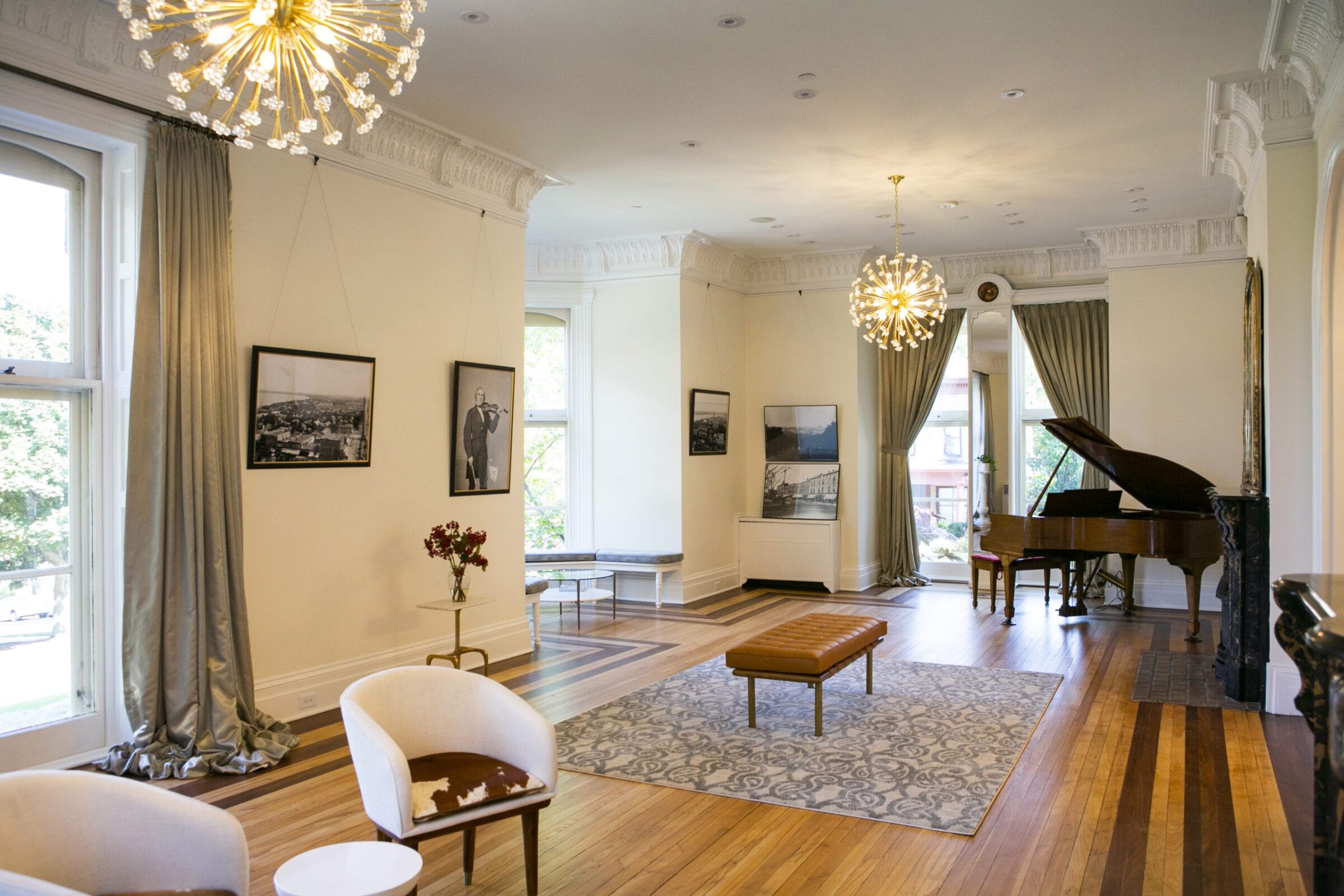 Grand piano, ornate chandeliers, and artwork in a well-decorated room.