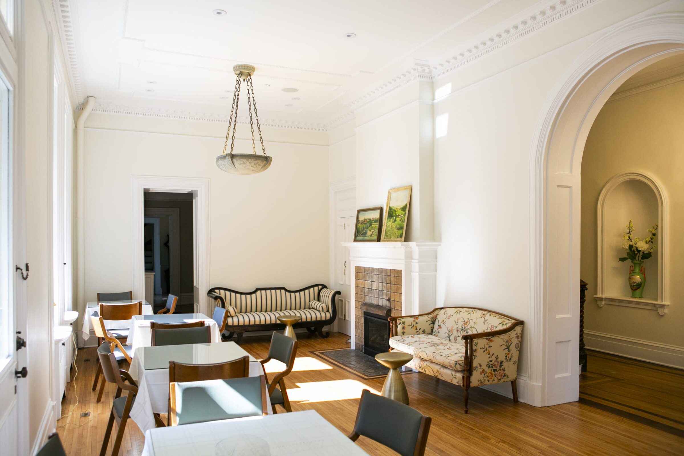 Dining room with tables, chairs, fireplace, and two sofas.