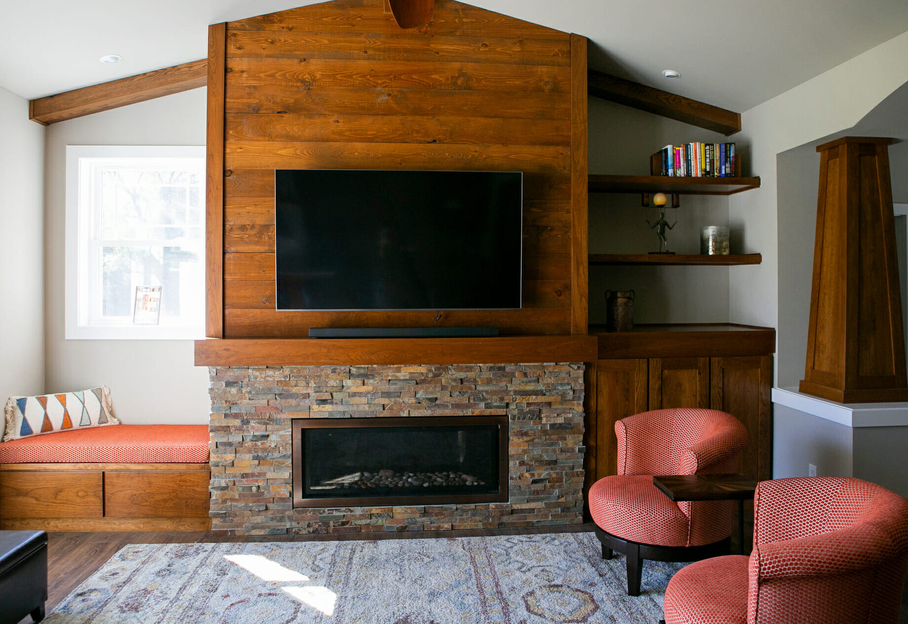 Cozy living room featuring a wooden accent wall, stone fireplace, and two round chairs with a small table.