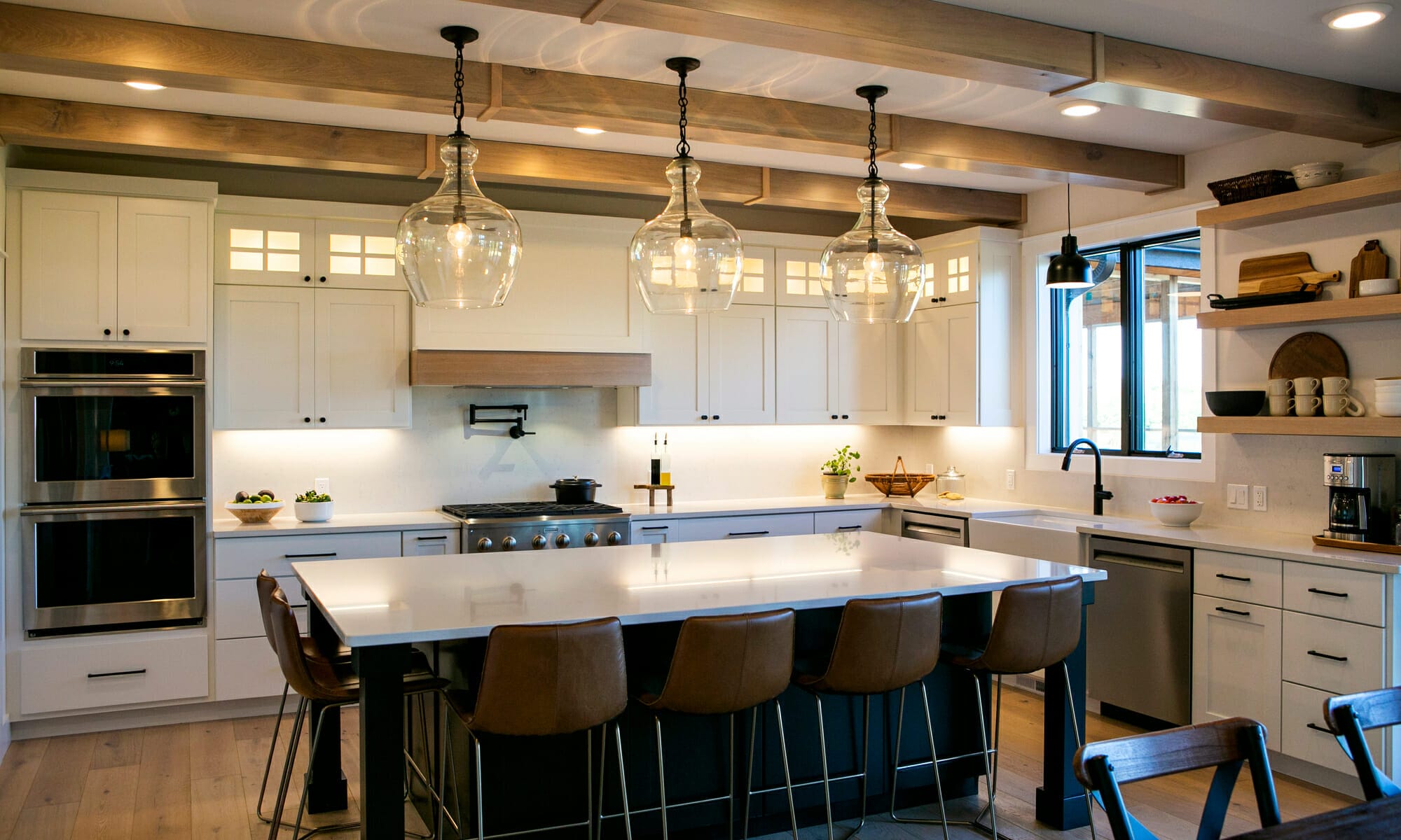 Modern kitchen featuring white cabinetry, a large island with bar stools, and stylish pendant lighting.