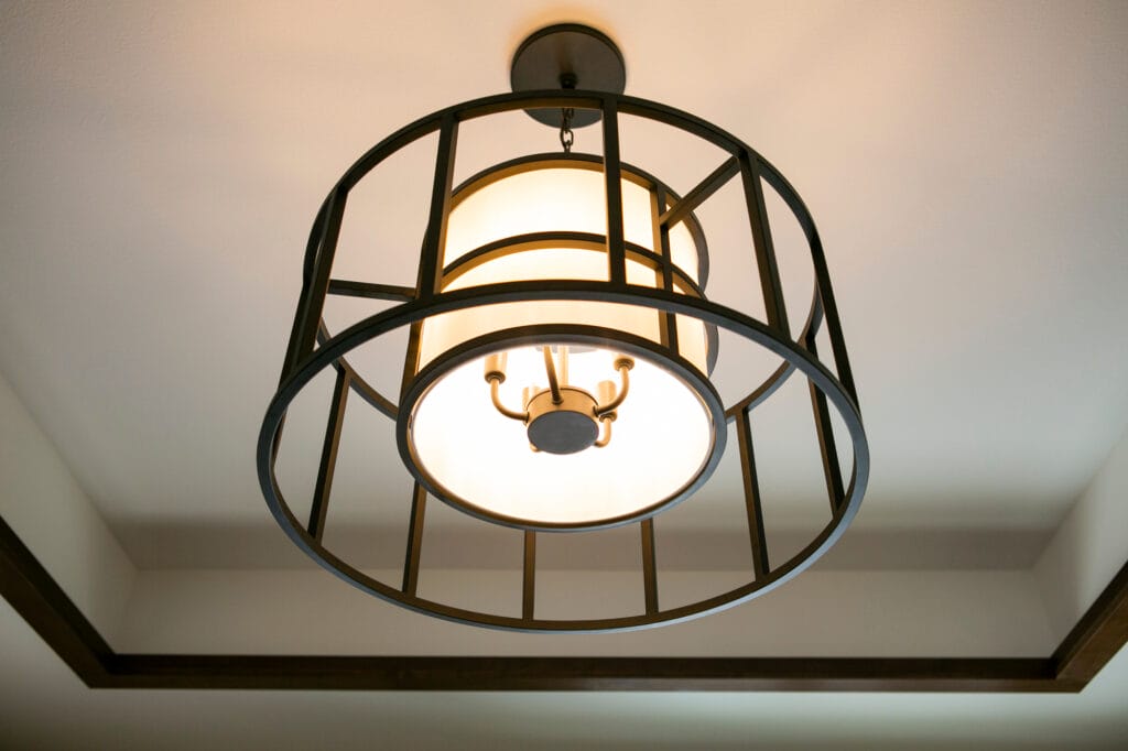 Modern ceiling light fixture with a black metal frame and frosted glass, illuminating a neutral-colored ceiling.