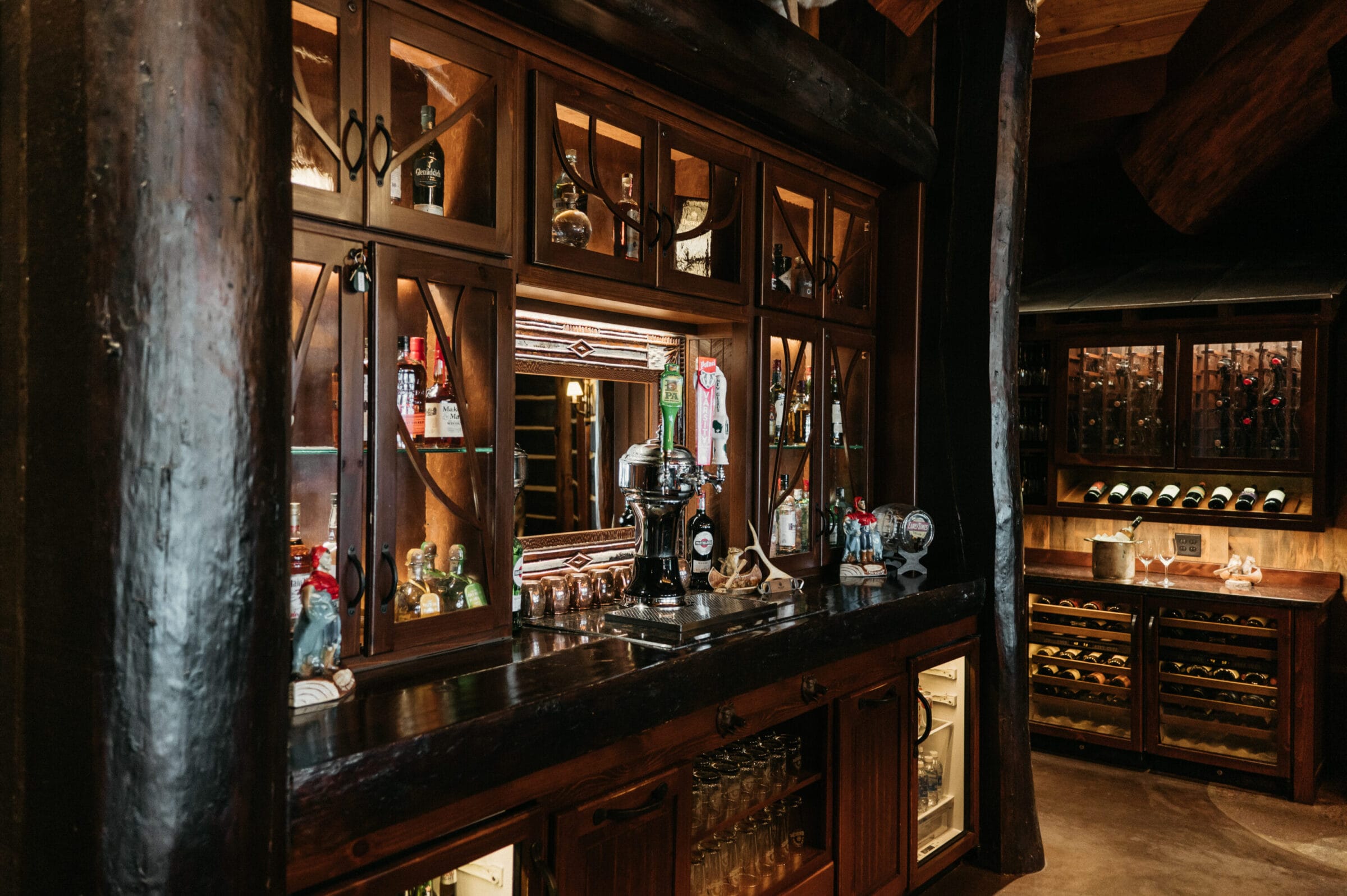 Rustic wooden bar with shelves displaying various bottles, a mirror, and a wine rack, creating a cozy atmosphere.