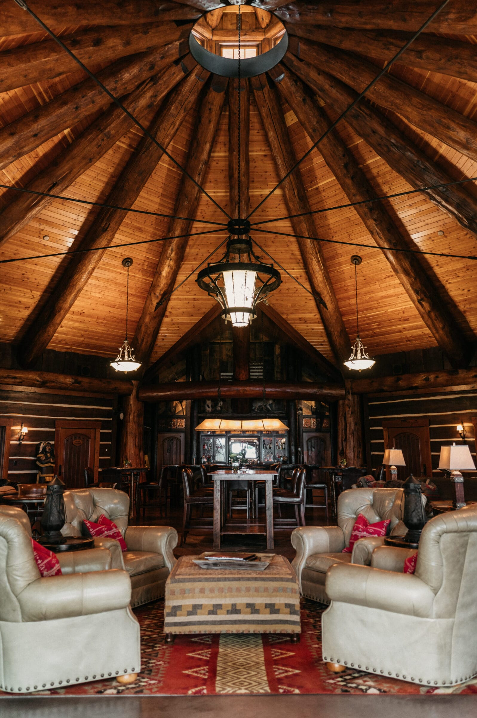Rustic lodge interior featuring a high wooden ceiling, cozy seating, and a central dining area with warm lighting.