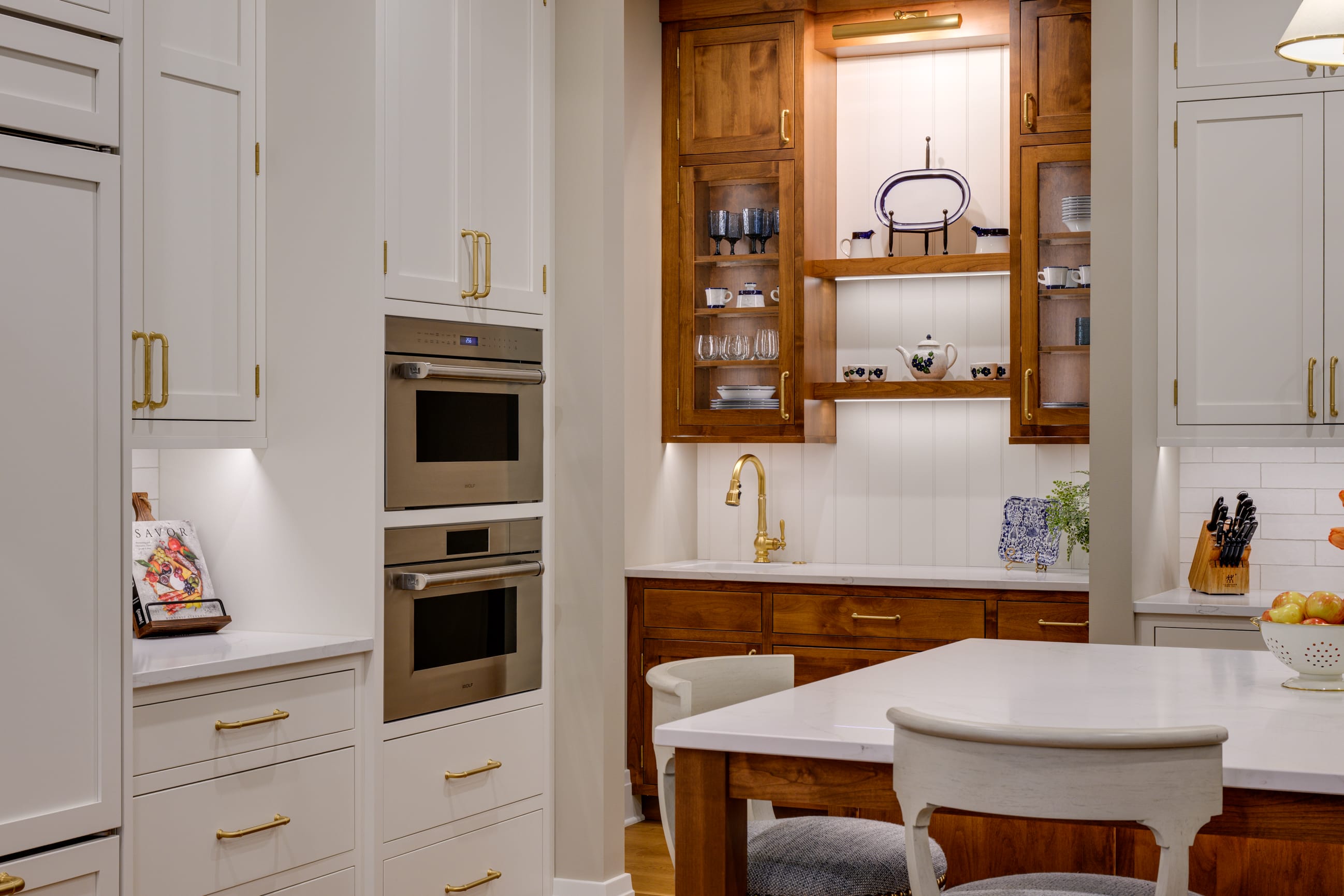 Modern kitchen featuring white cabinetry, stainless steel appliances, wooden accents, and a stylish dining table.