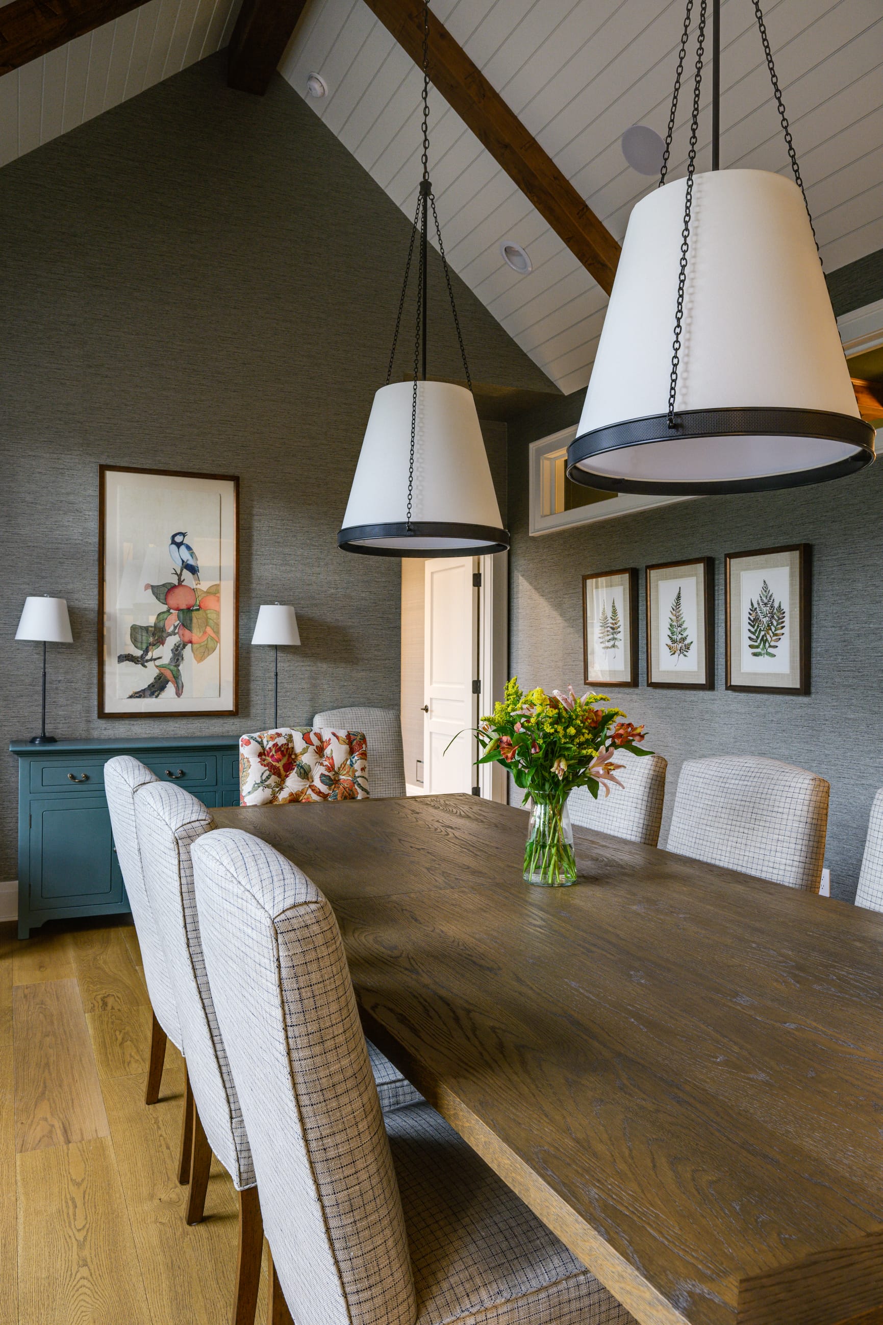 Stylish dining room with a wooden table, patterned chairs, floral centerpiece, and modern pendant lights.