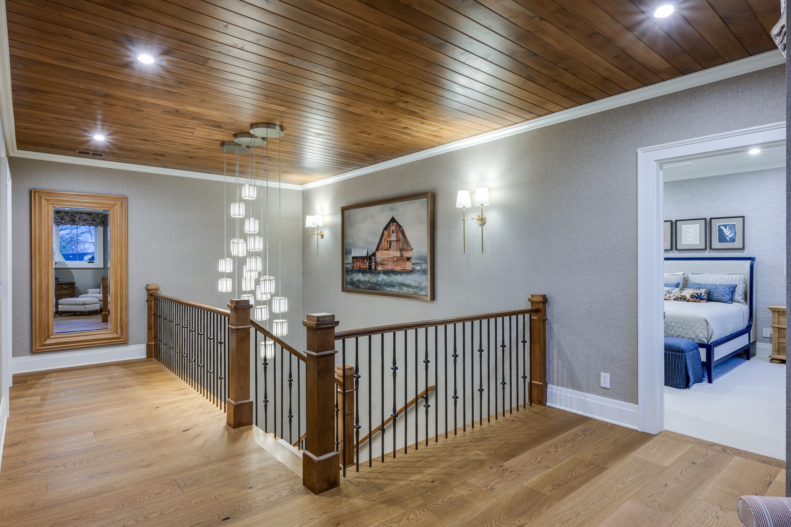 Stylish hallway with wooden ceiling, modern light fixtures, and a large mirror, leading to a cozy bedroom.