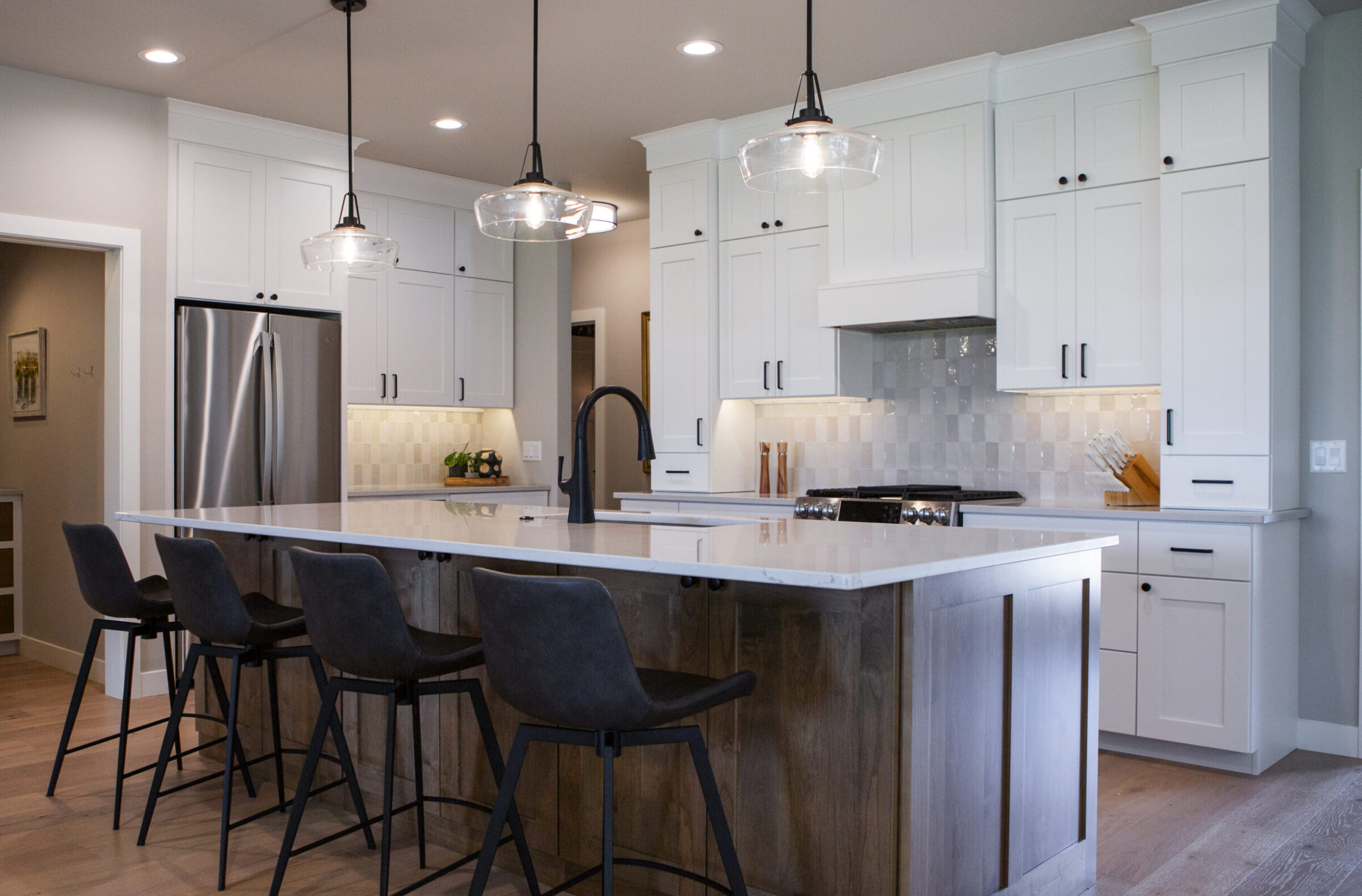 Modern kitchen with white cabinets, island with seating, and stainless steel appliances.