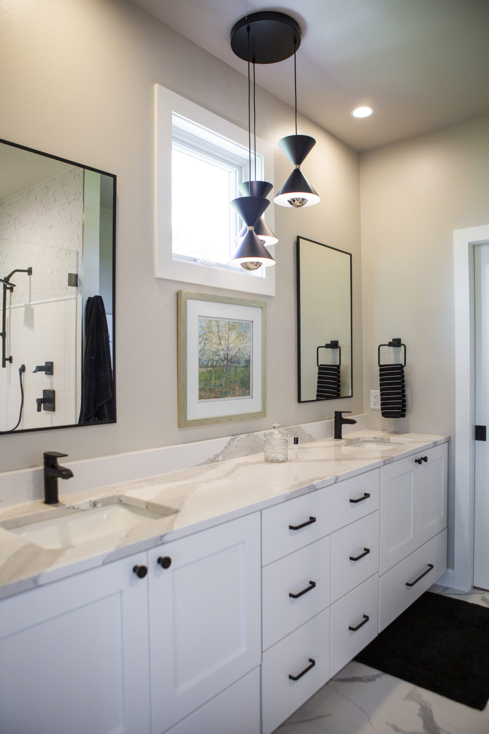 Modern bathroom vanity with dual sinks, marble countertop, and a trio of pendant lights.