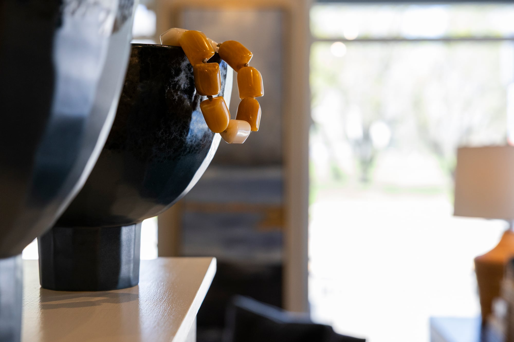 Beaded bracelet draped over a dark ceramic bowl.