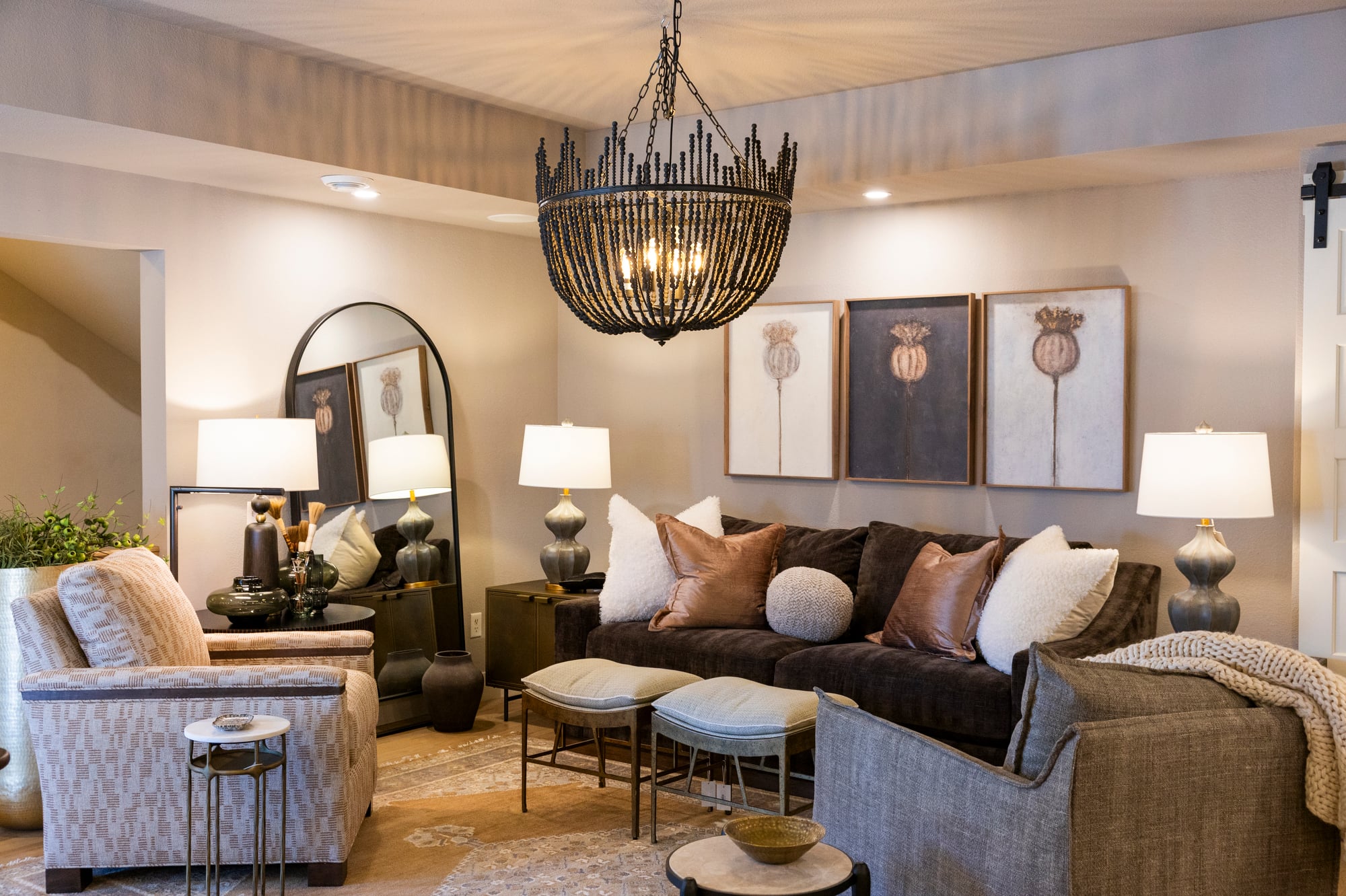 Living room with dark sofa, patterned armchair, three poppy art prints, and ornate chandelier.