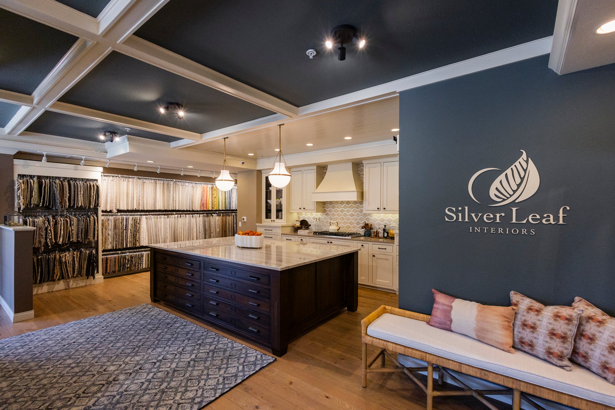 Kitchen showroom with fabric samples, island, and Silver Leaf Interiors logo.