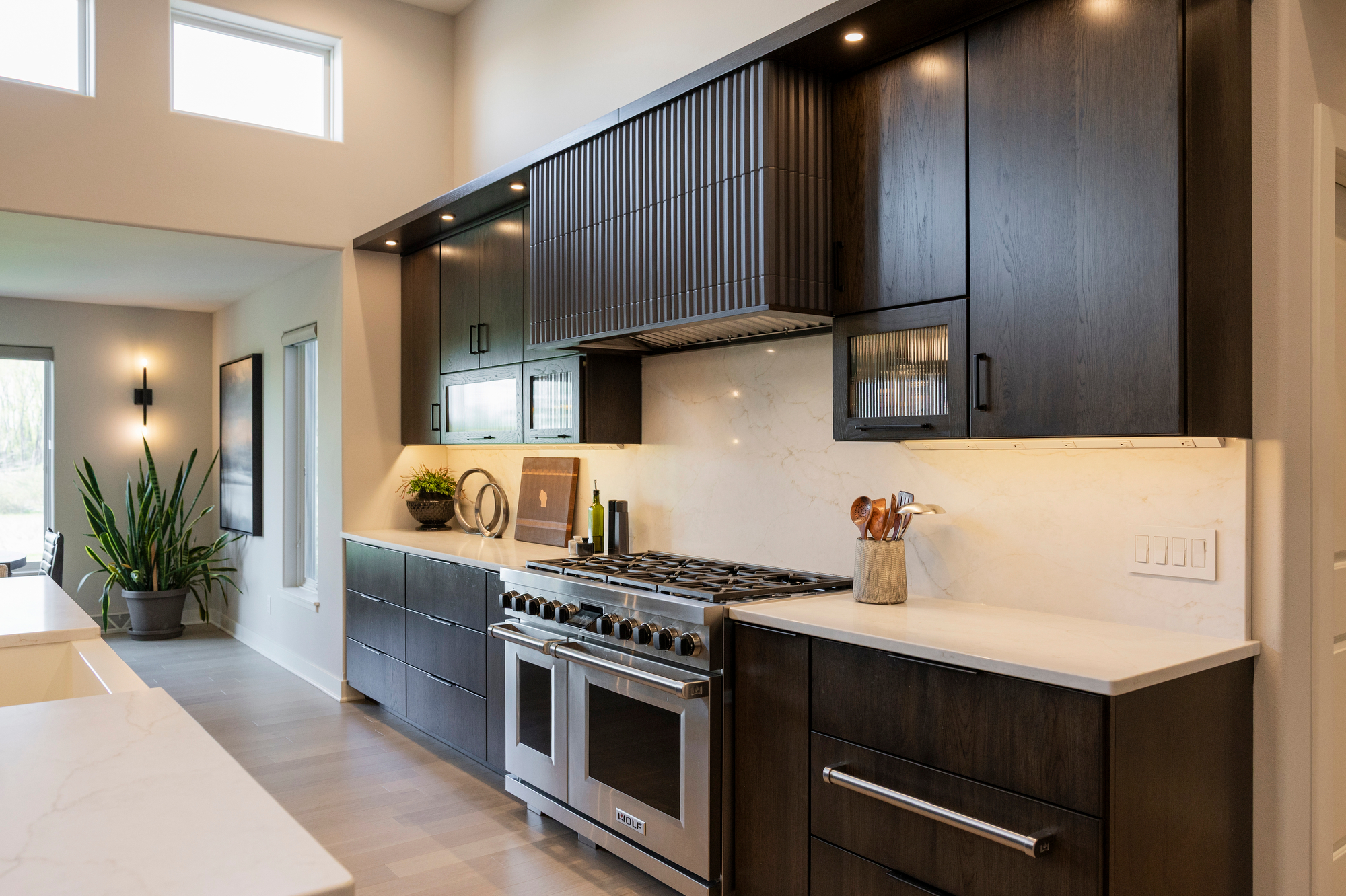Modern kitchen with dark wood cabinets, stainless steel range, and marble backsplash.
