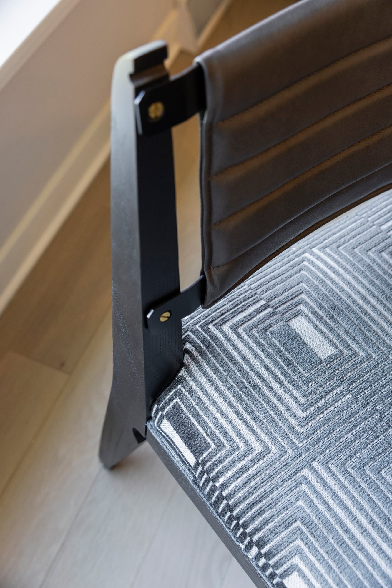 Modern chair with dark wood frame, gray leather back, and geometric patterned seat.
