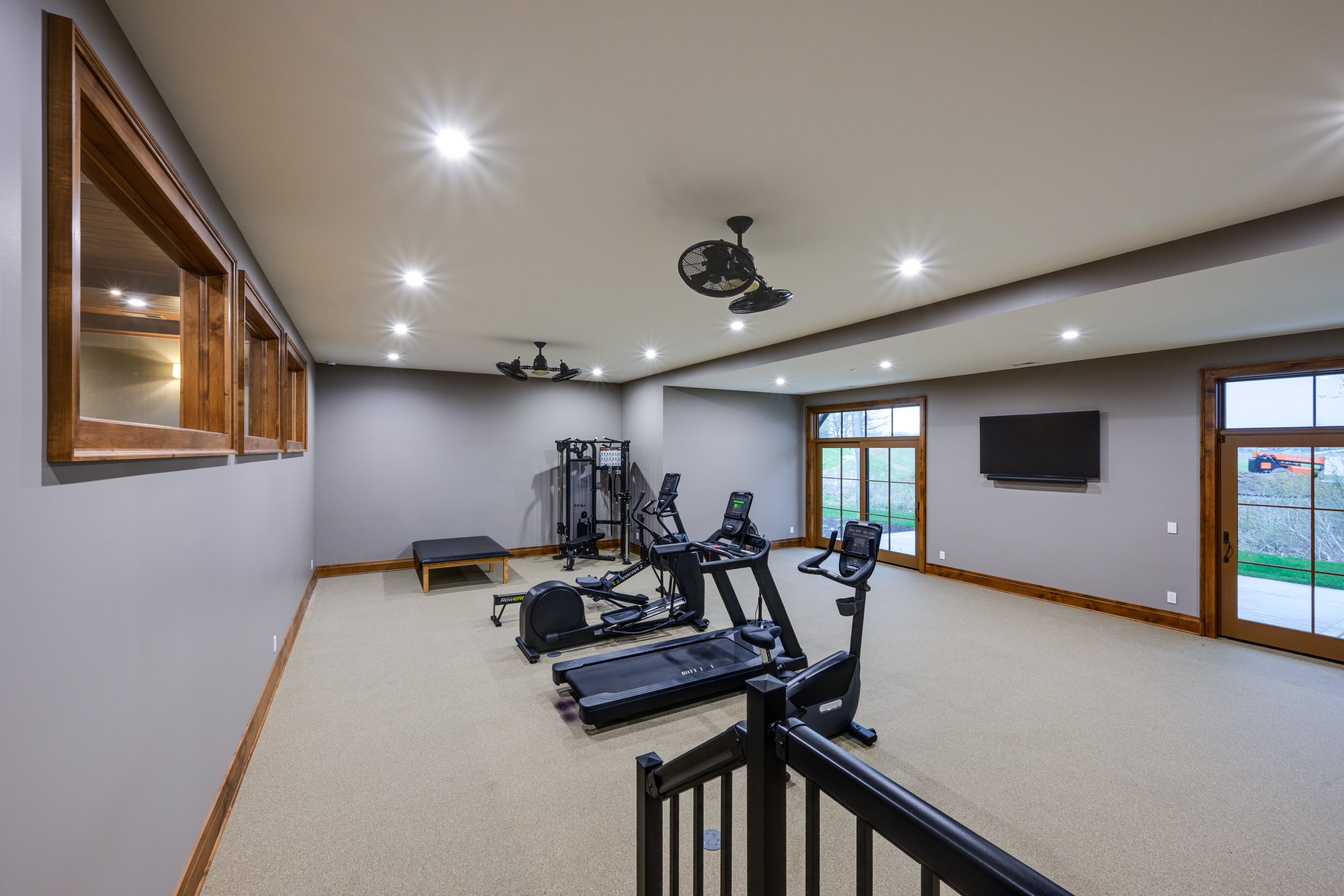 Home gym with treadmill, elliptical, stationary bike, and weight machine.