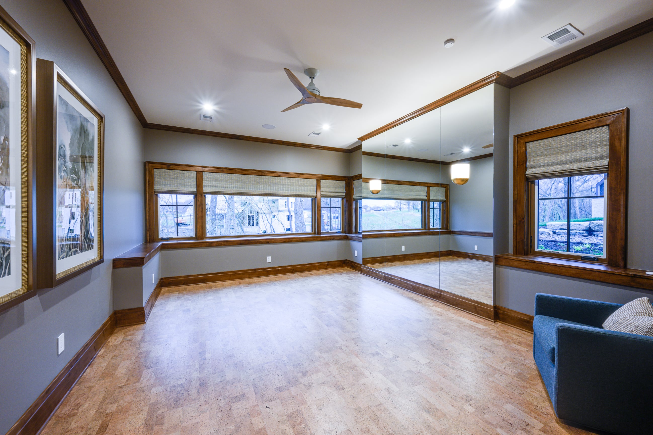 Room with large mirrors, wood trim, and a ceiling fan.