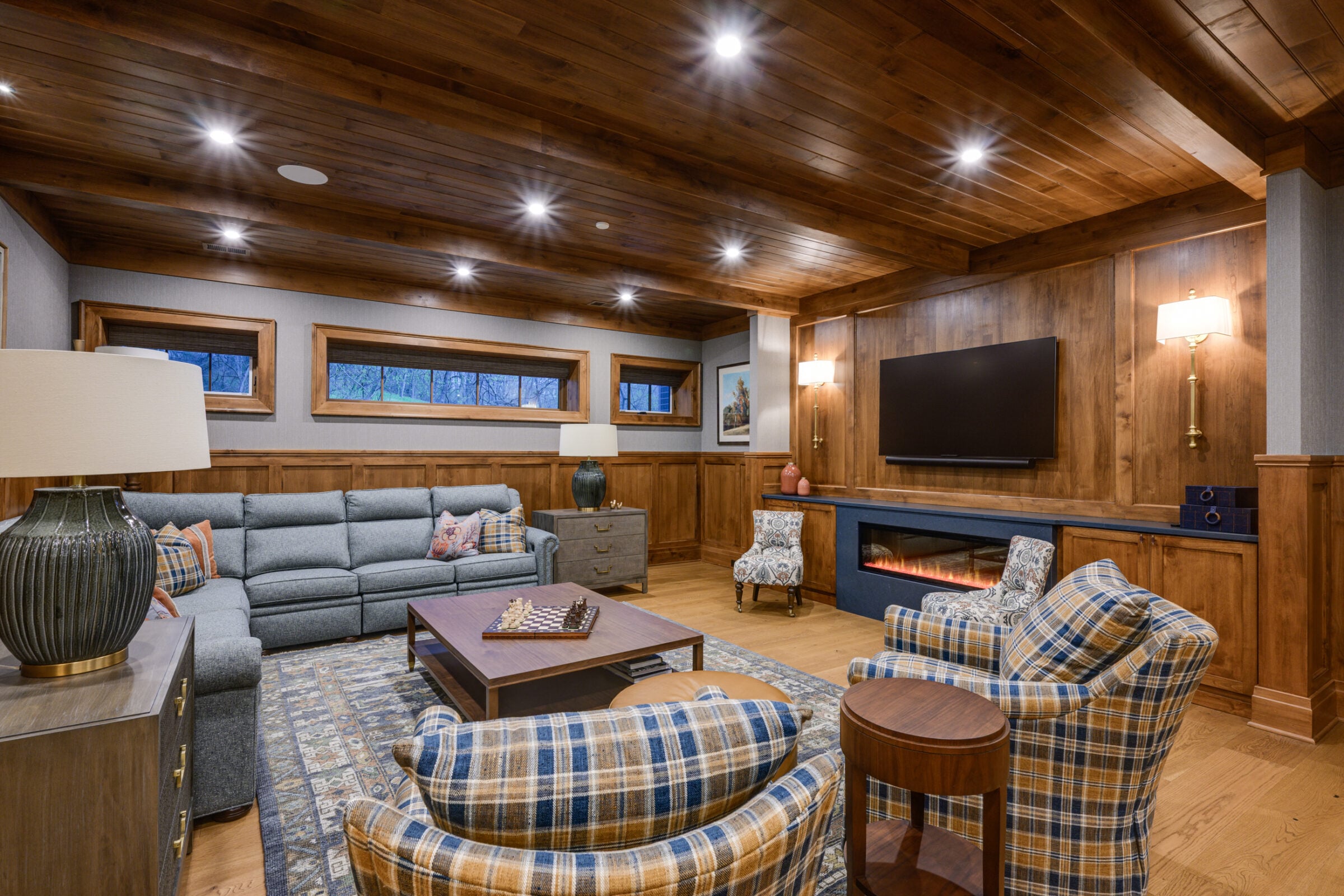 Cozy living room with sectional sofa, plaid armchairs, fireplace, and TV.