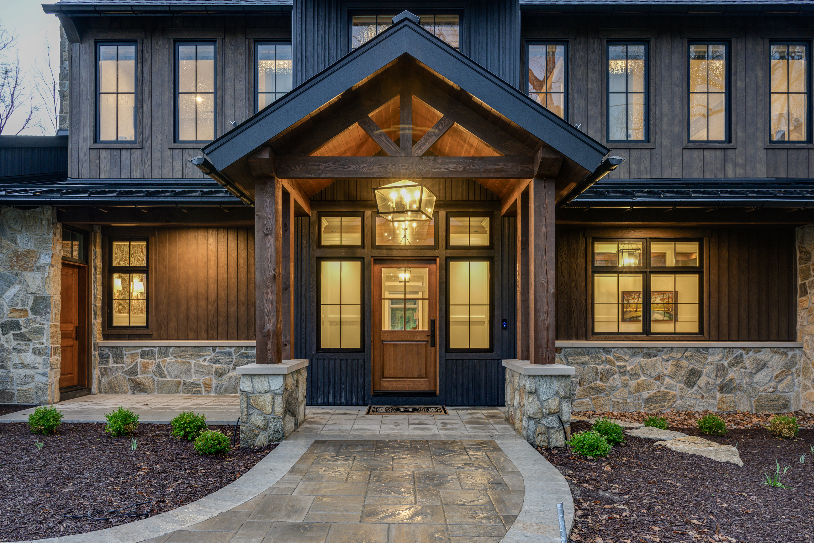 Rustic wooden porch with stone accents and a large lantern over the front door.