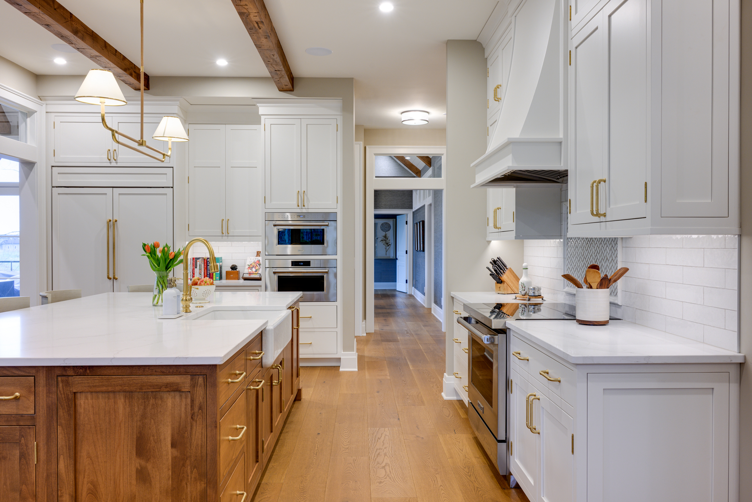 Modern kitchen with white cabinets, wood island, and gold hardware.