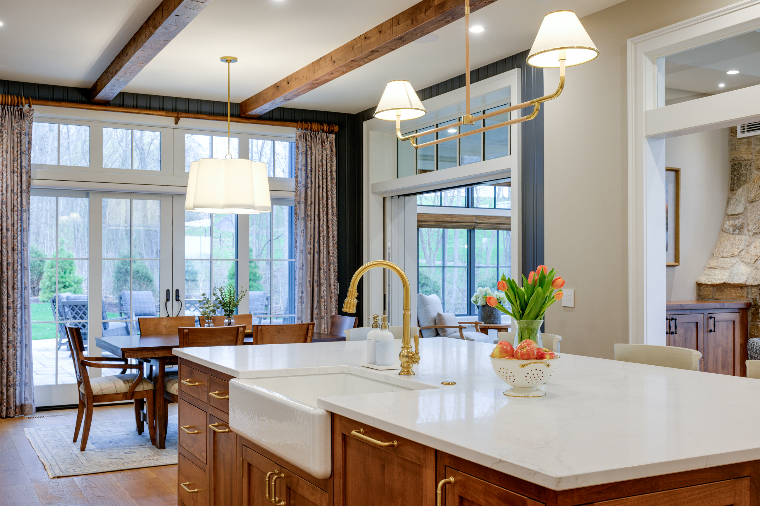 Kitchen island with white sink and gold faucet, tulips, and fruit bowl.