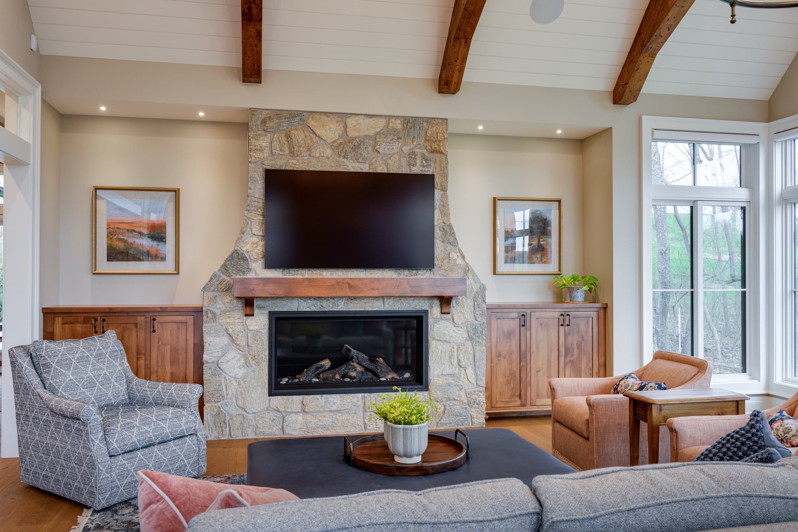 Living room with stone fireplace, mounted TV, and cozy seating.