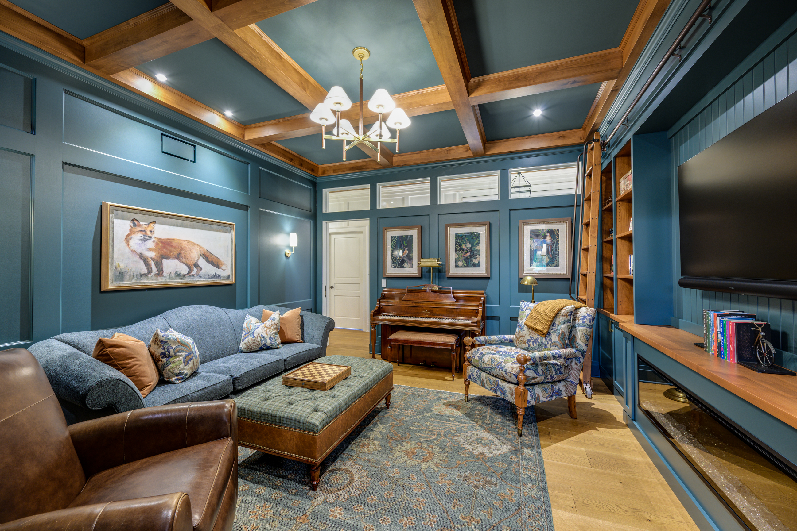 Cozy den with blue walls, coffered ceiling, fox painting, piano, and plush seating.