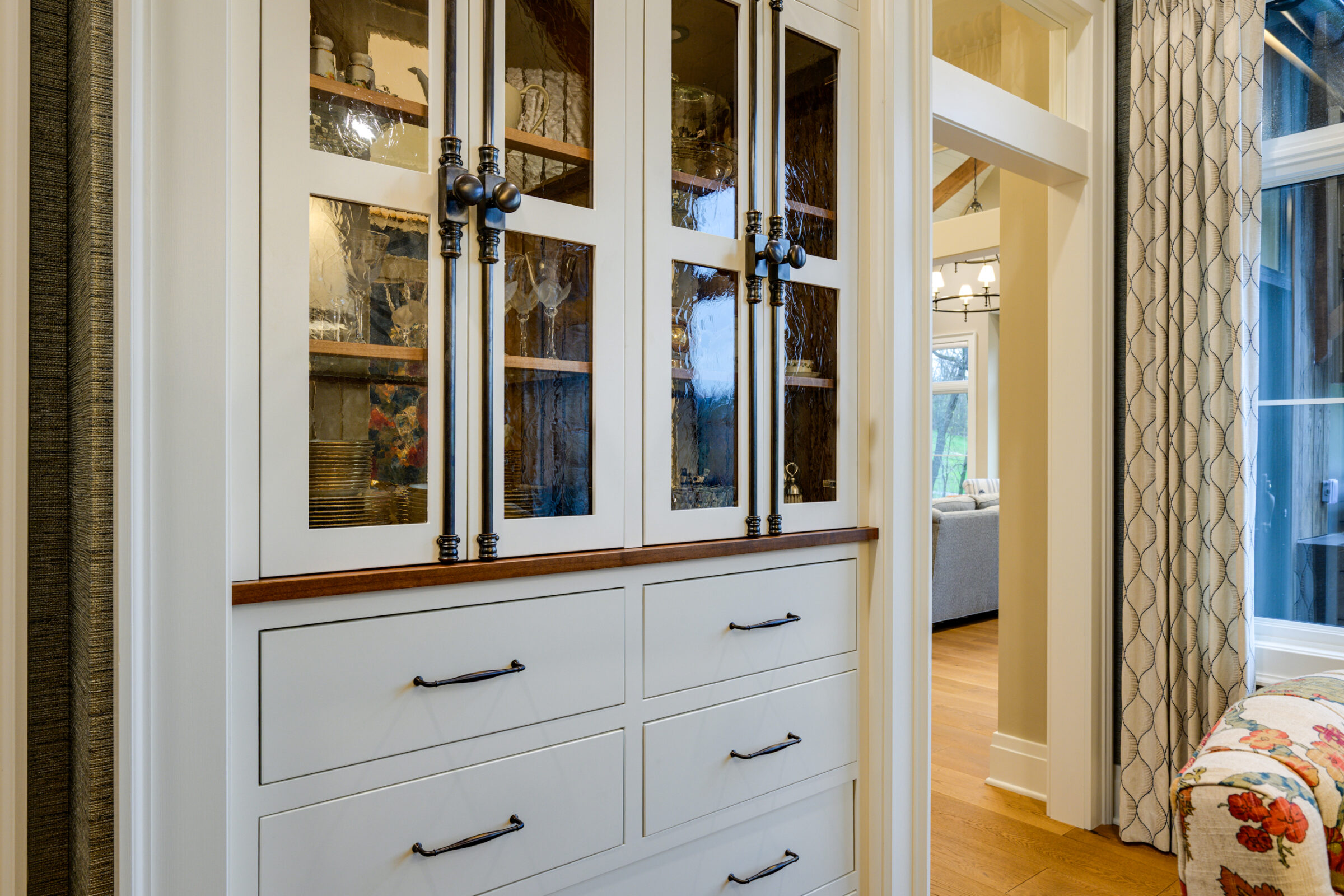 White china cabinet with glass doors and drawers, displaying dishes and glassware.