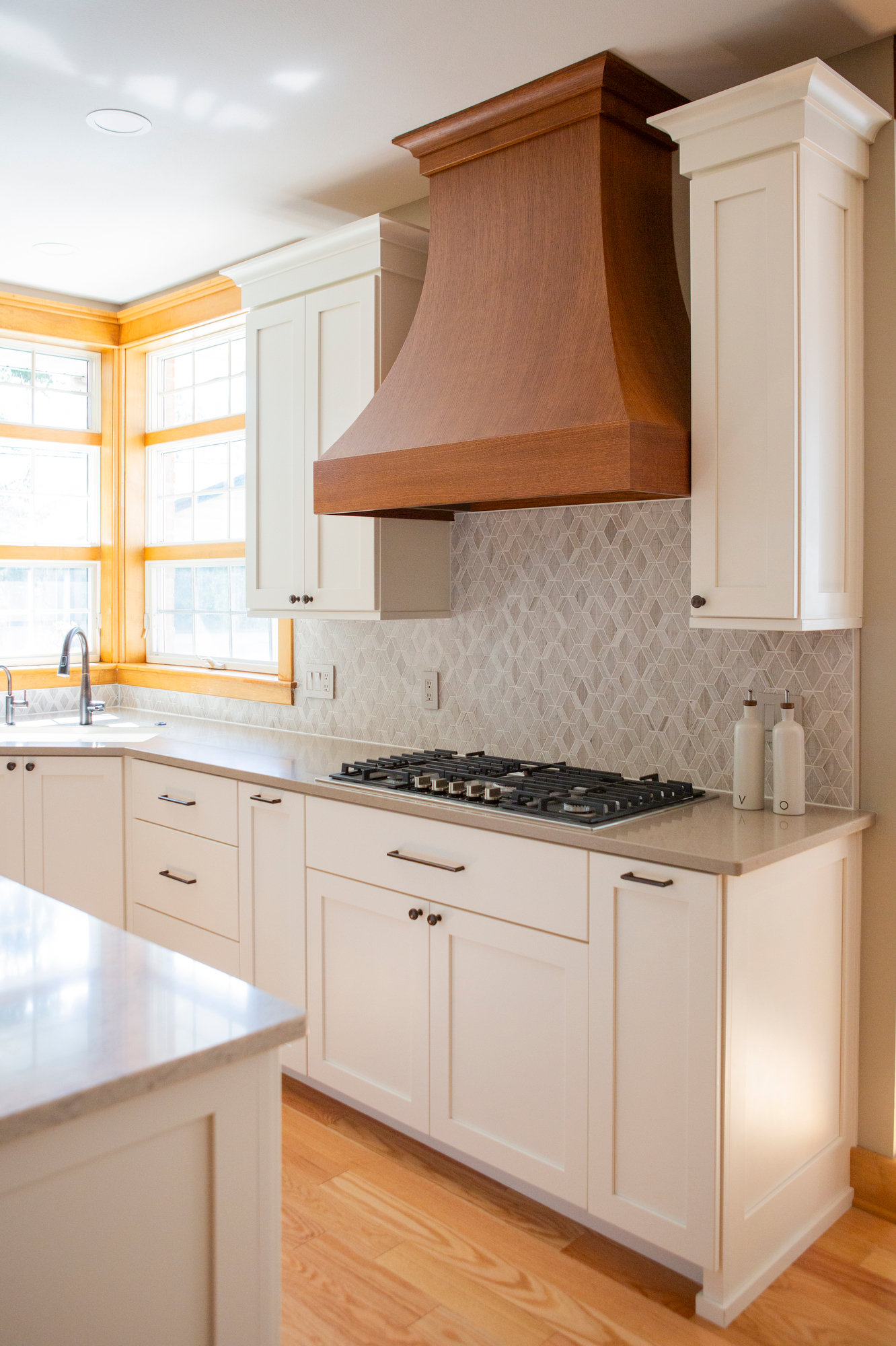 Kitchen with white cabinets, gas stove, and a prominent wooden range hood.