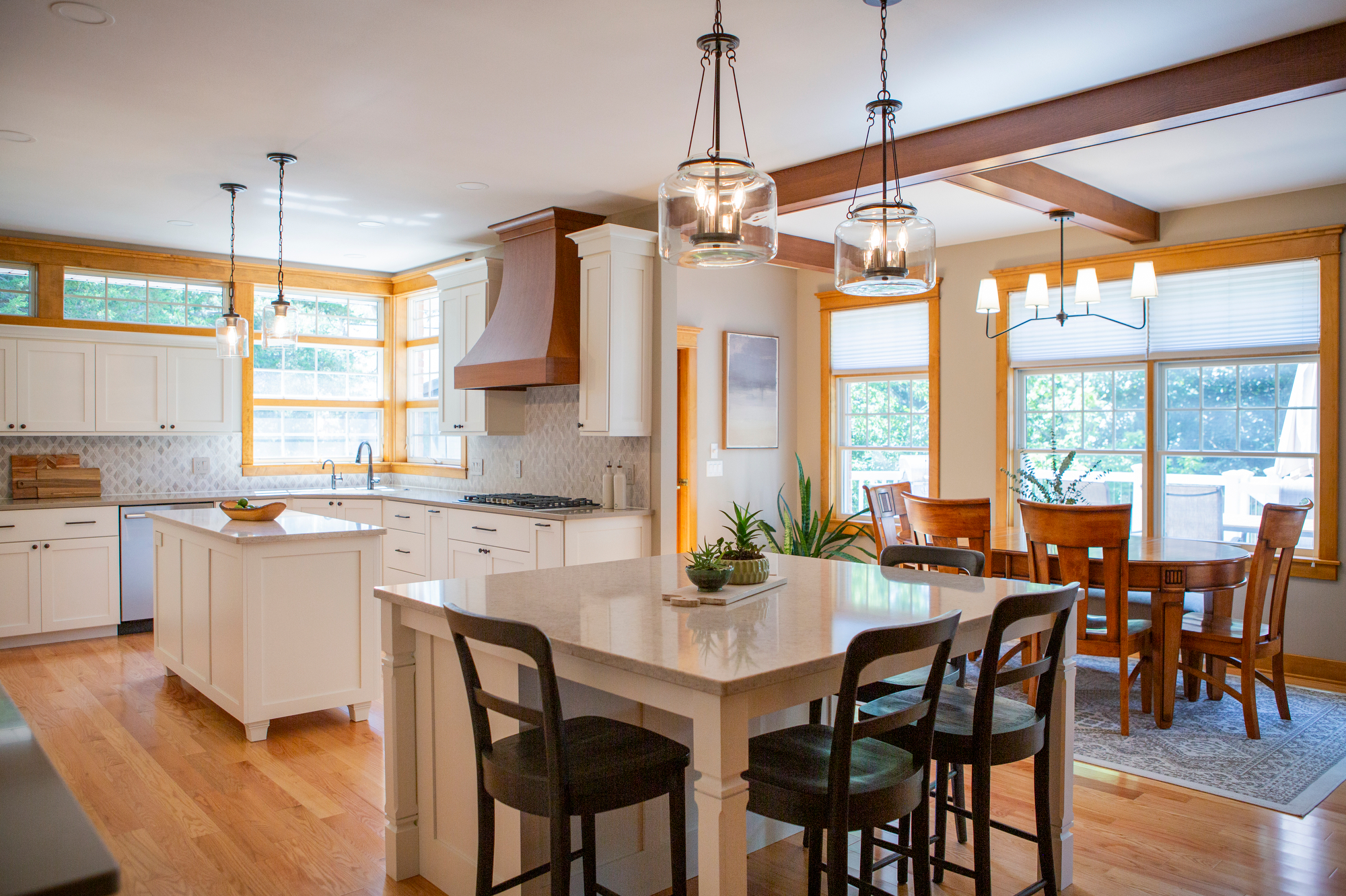 Bright kitchen with white cabinets, island, dining table, and wood beams.