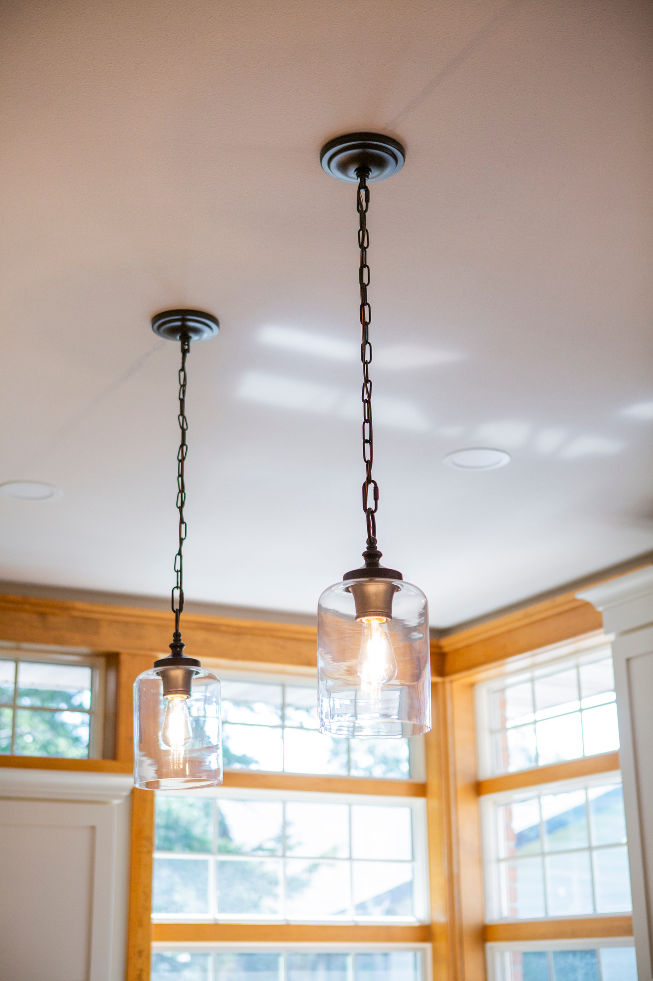 Two clear glass pendant lights with Edison bulbs hang from dark chains against a white ceiling.