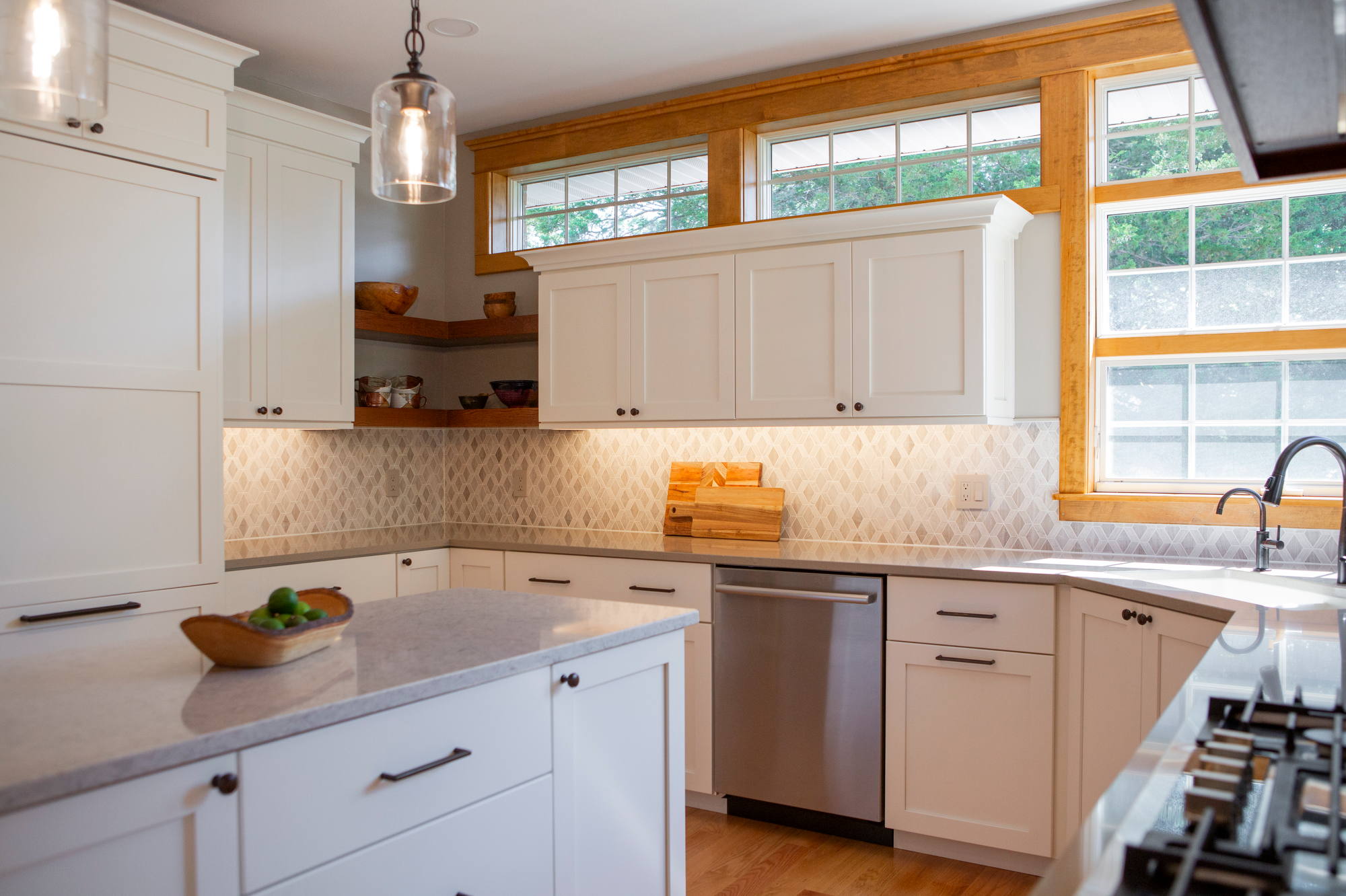 Modern white kitchen with stainless steel appliances, granite countertops, and a wooden bowl of limes.