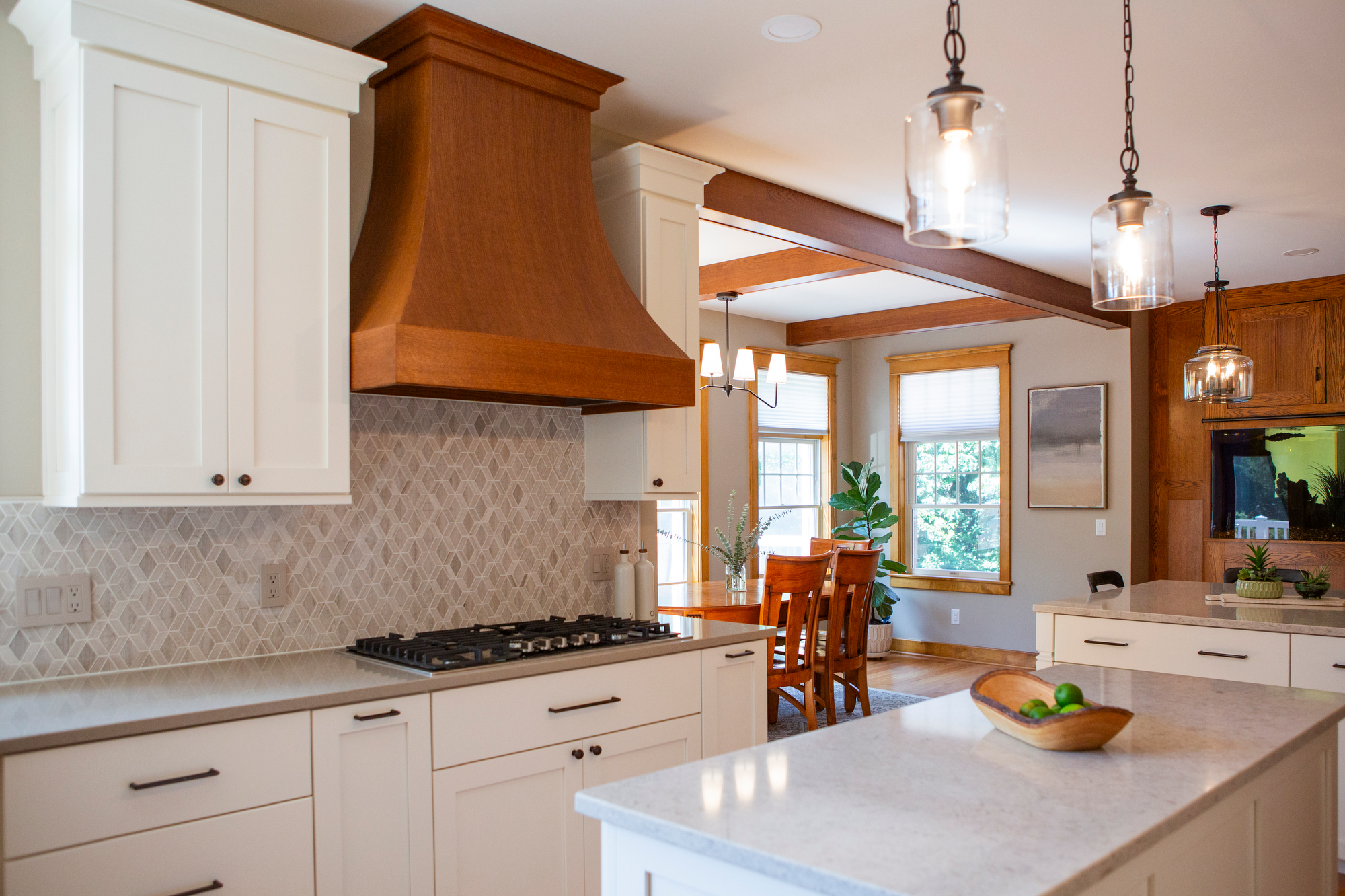 Modern kitchen with white cabinets, a wooden range hood, and a granite island.