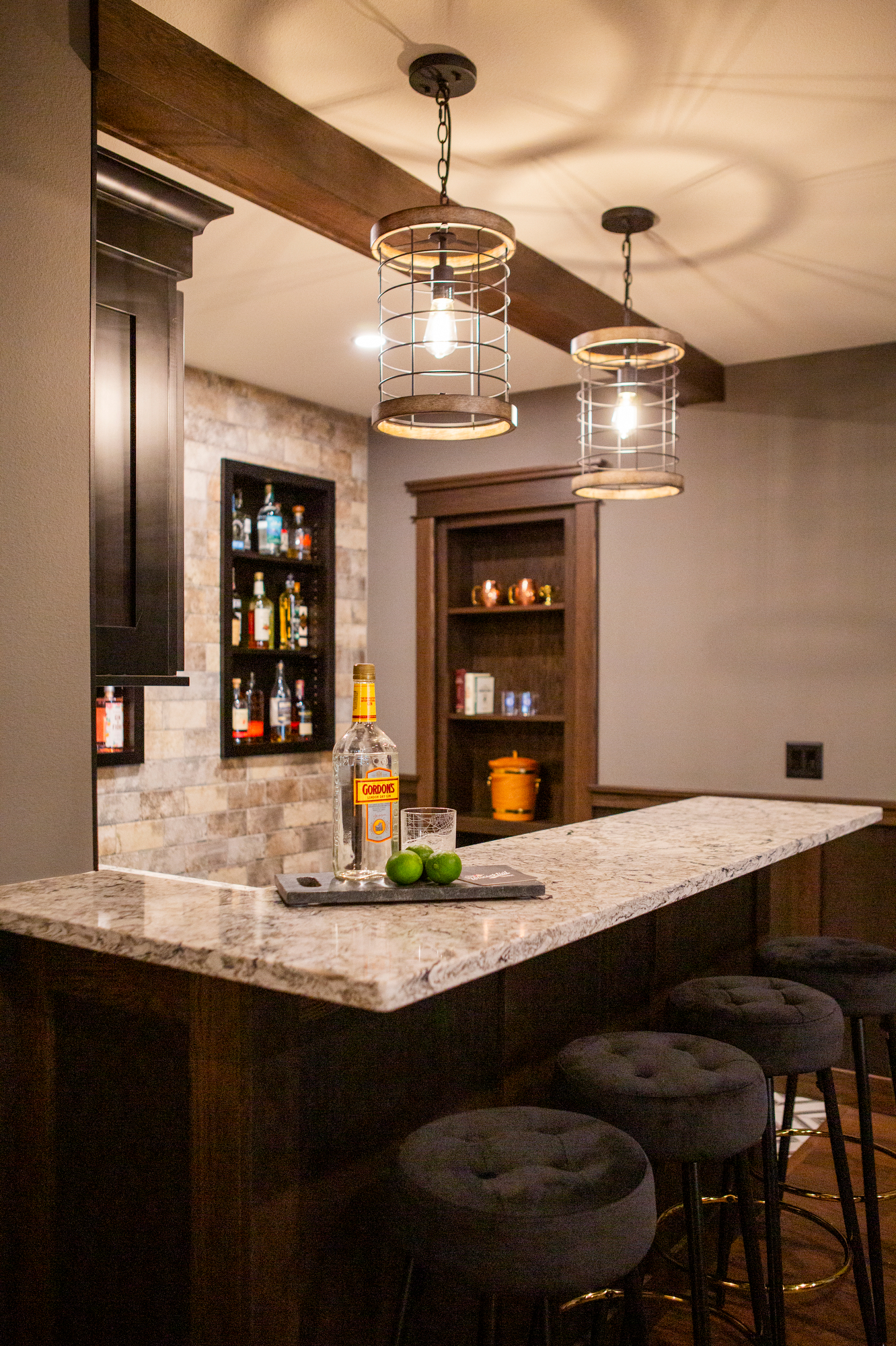 Home bar with granite counter, liquor bottles, and pendant lights.
