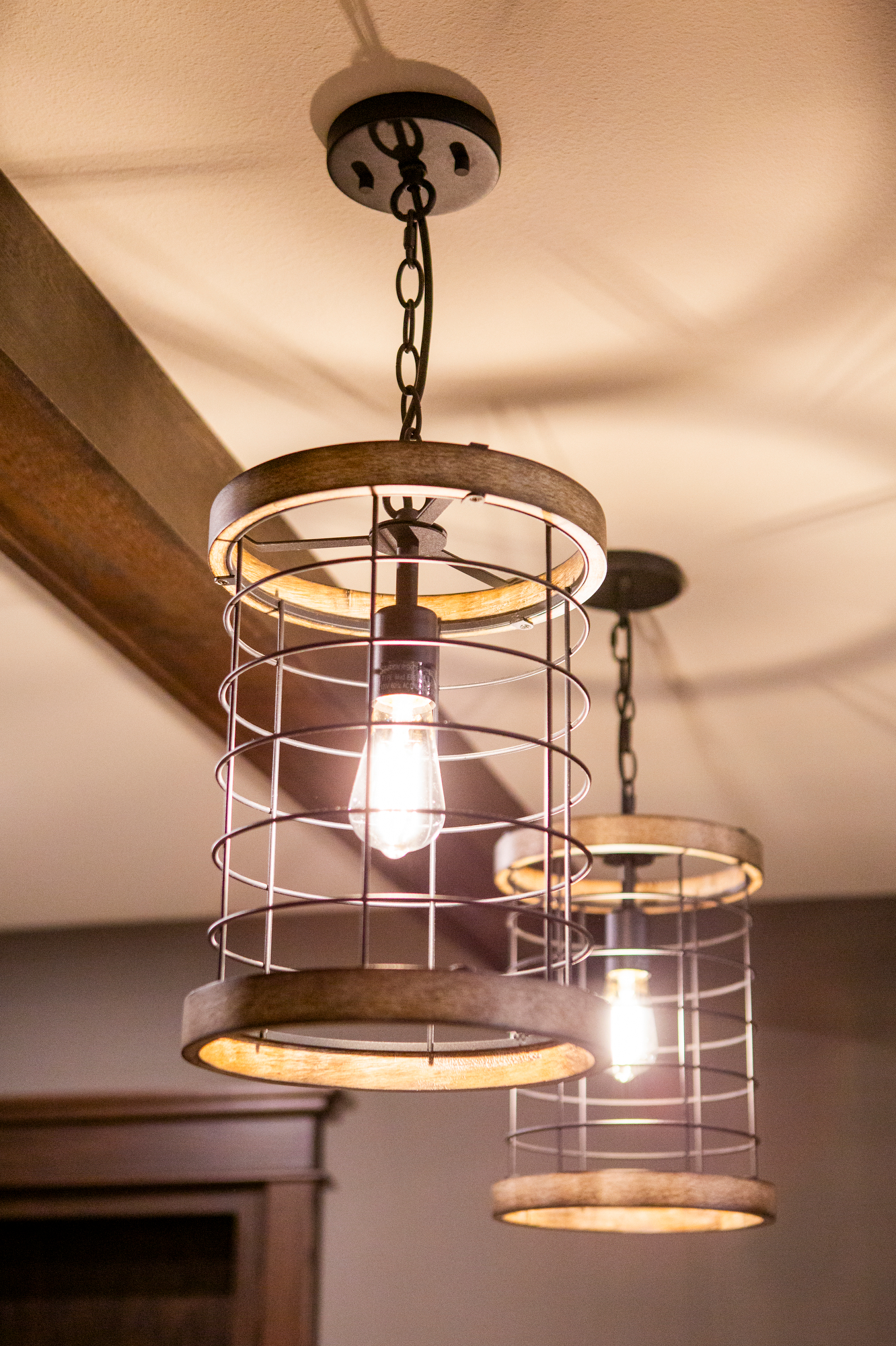 Two rustic pendant lights with metal cages and wooden rims hang from a ceiling.