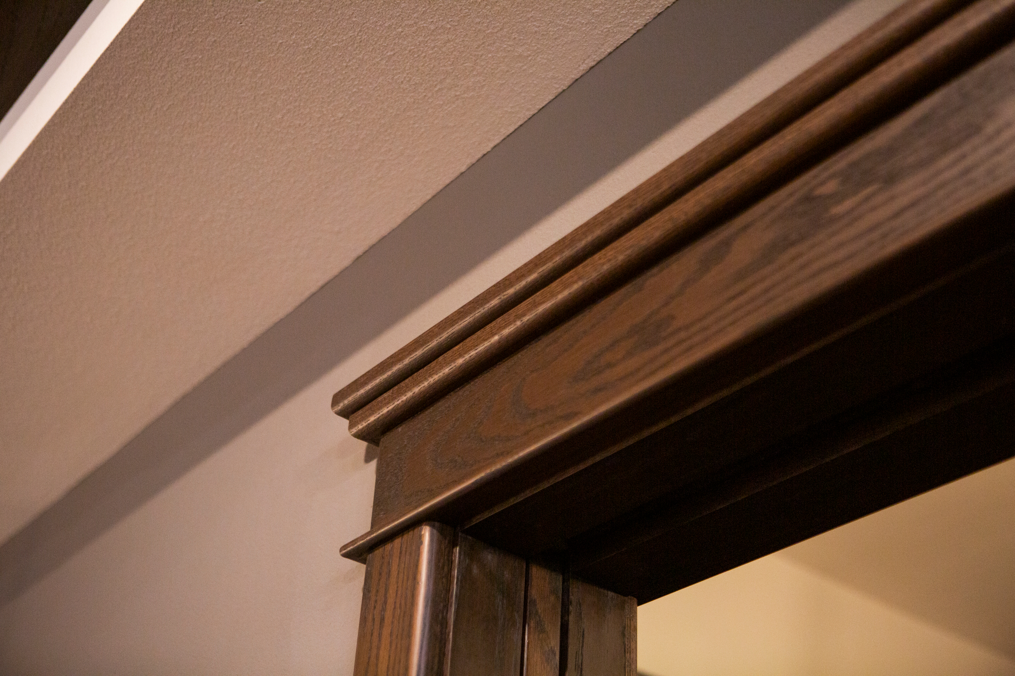 Dark wood door frame with decorative molding against a textured ceiling.