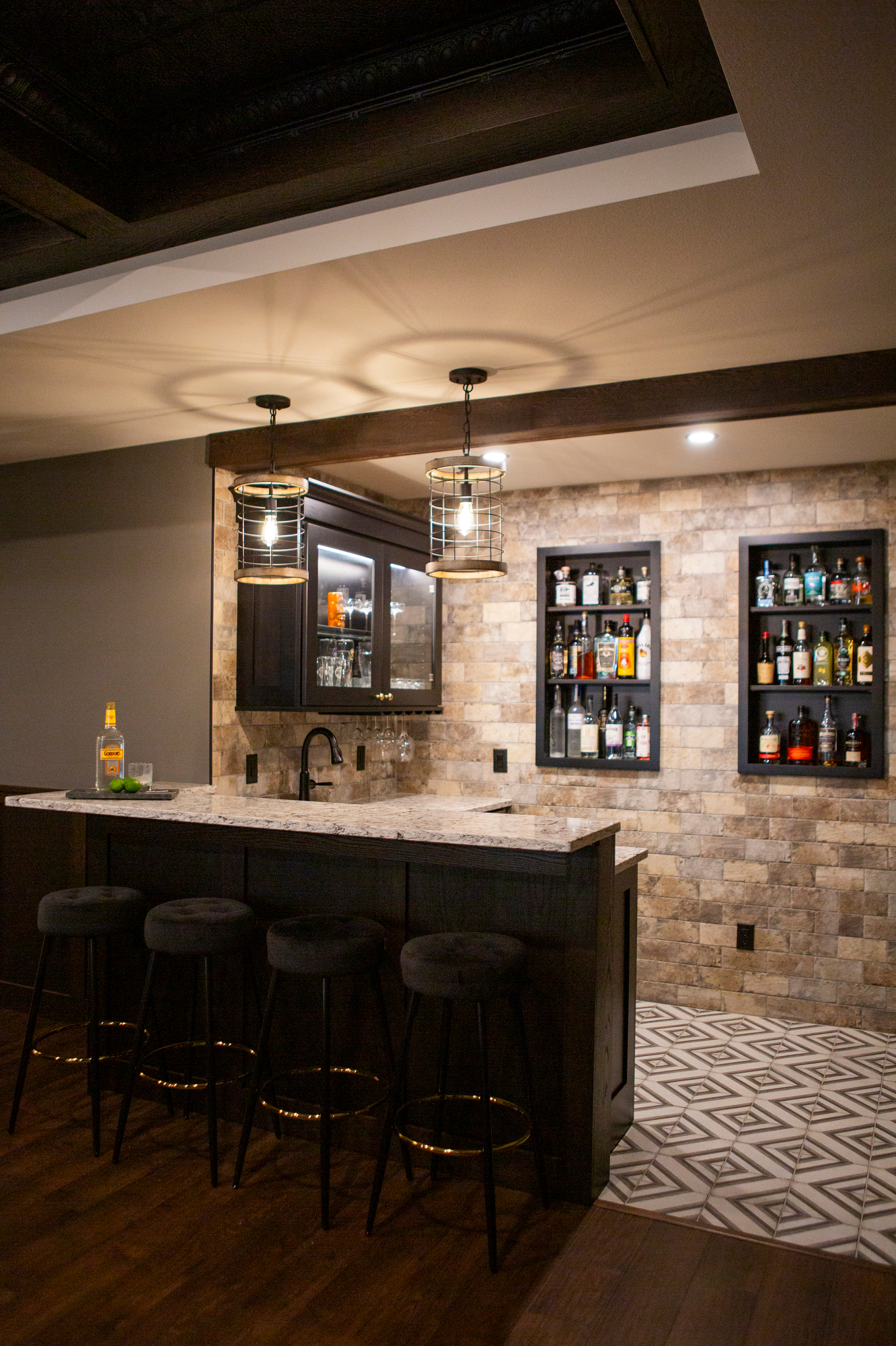 Home bar with dark wood, granite counter, four stools, and liquor shelves.