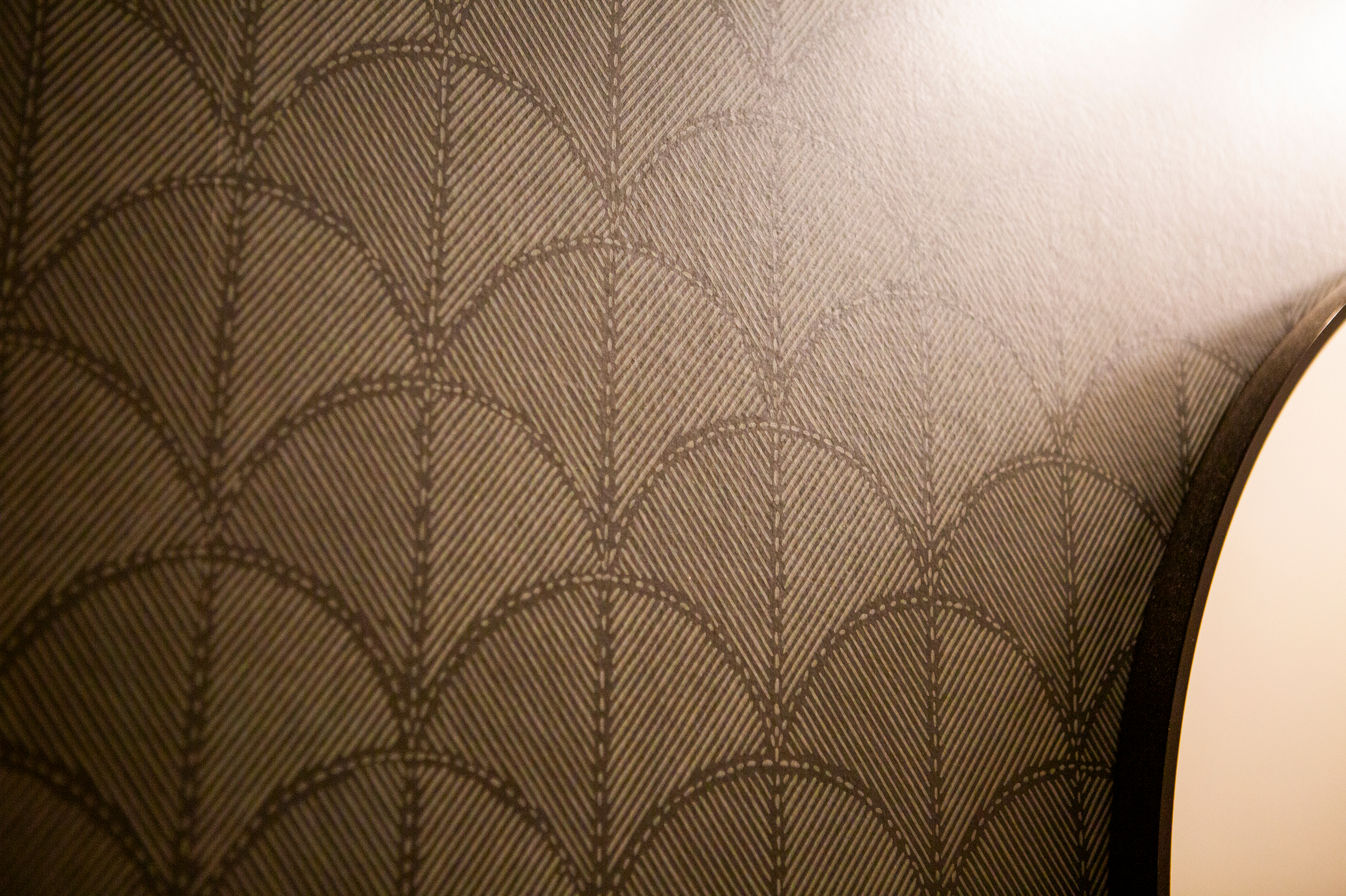 Art deco fan pattern wallpaper in dark brown with a textured appearance.