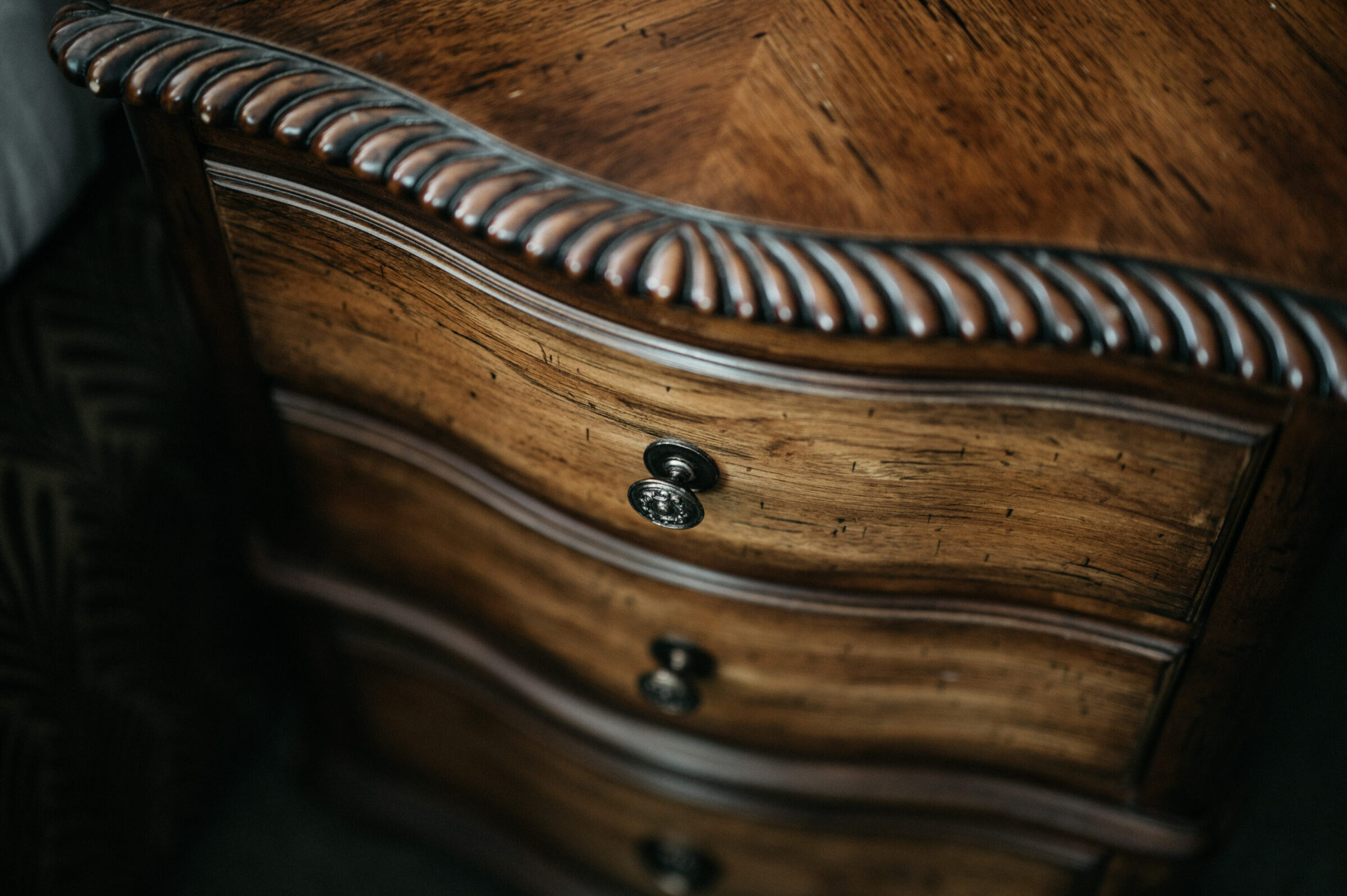 Ornate wooden dresser with three drawers and decorative trim.