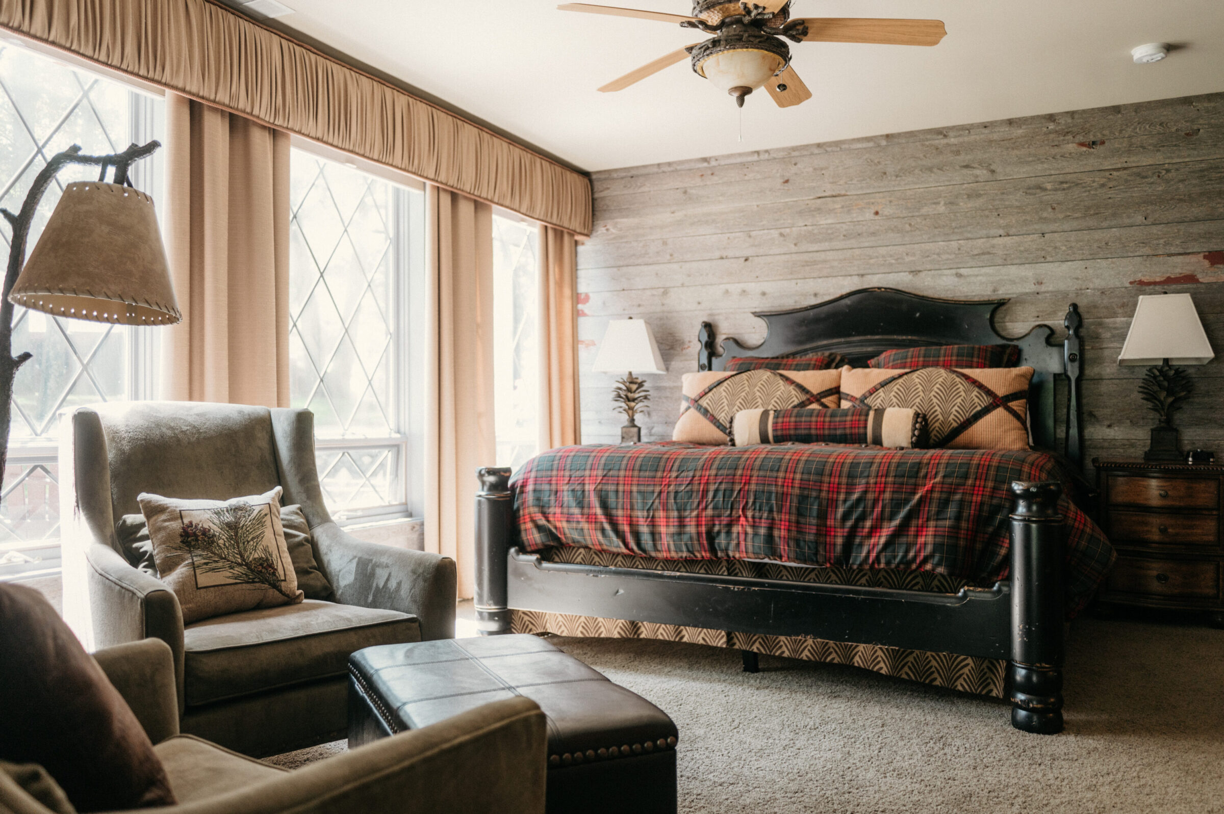 Rustic bedroom with plaid bedding, armchair, and wood-paneled wall.