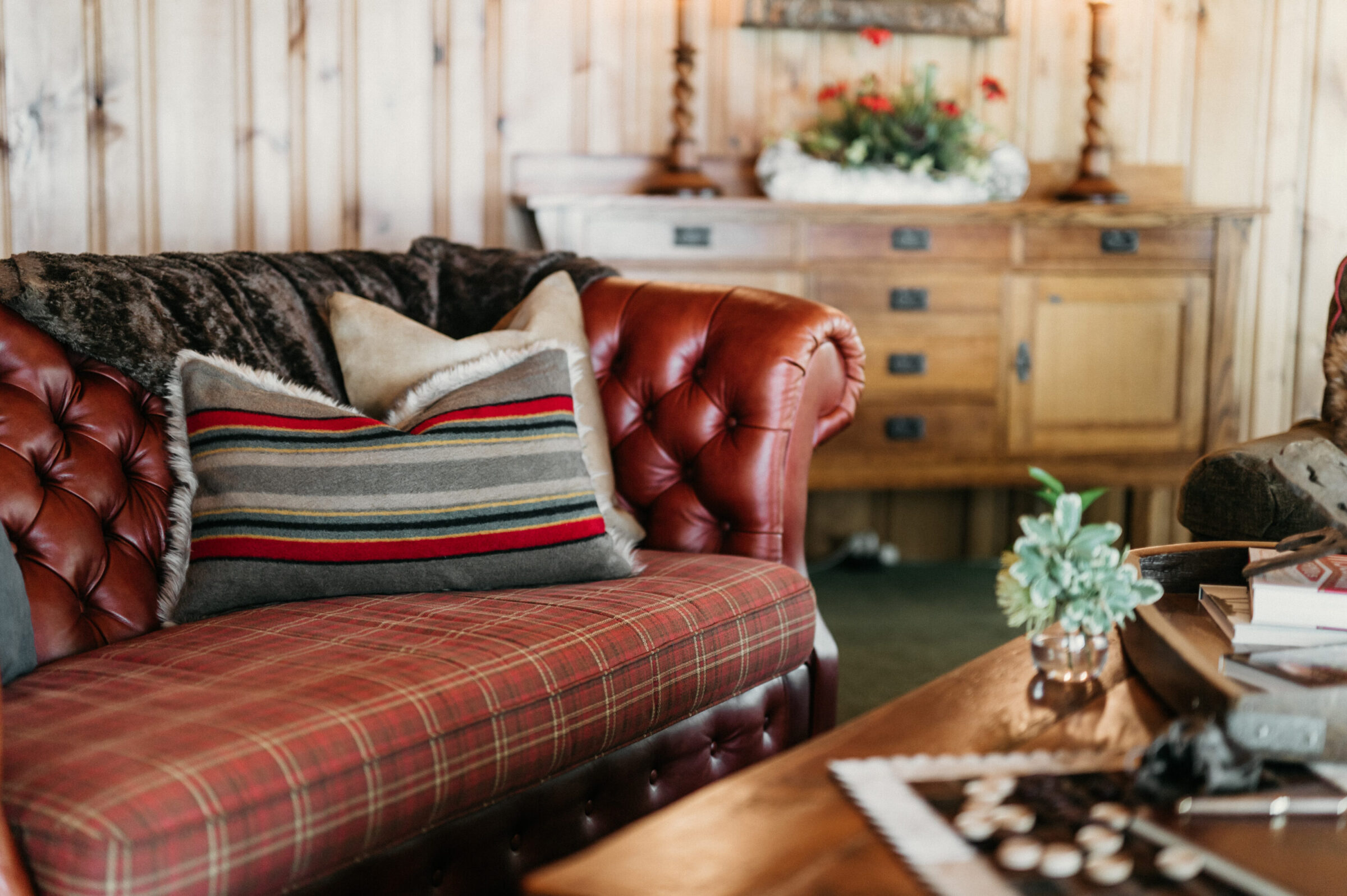 Tufted leather sofa with plaid cushions and a striped pillow.