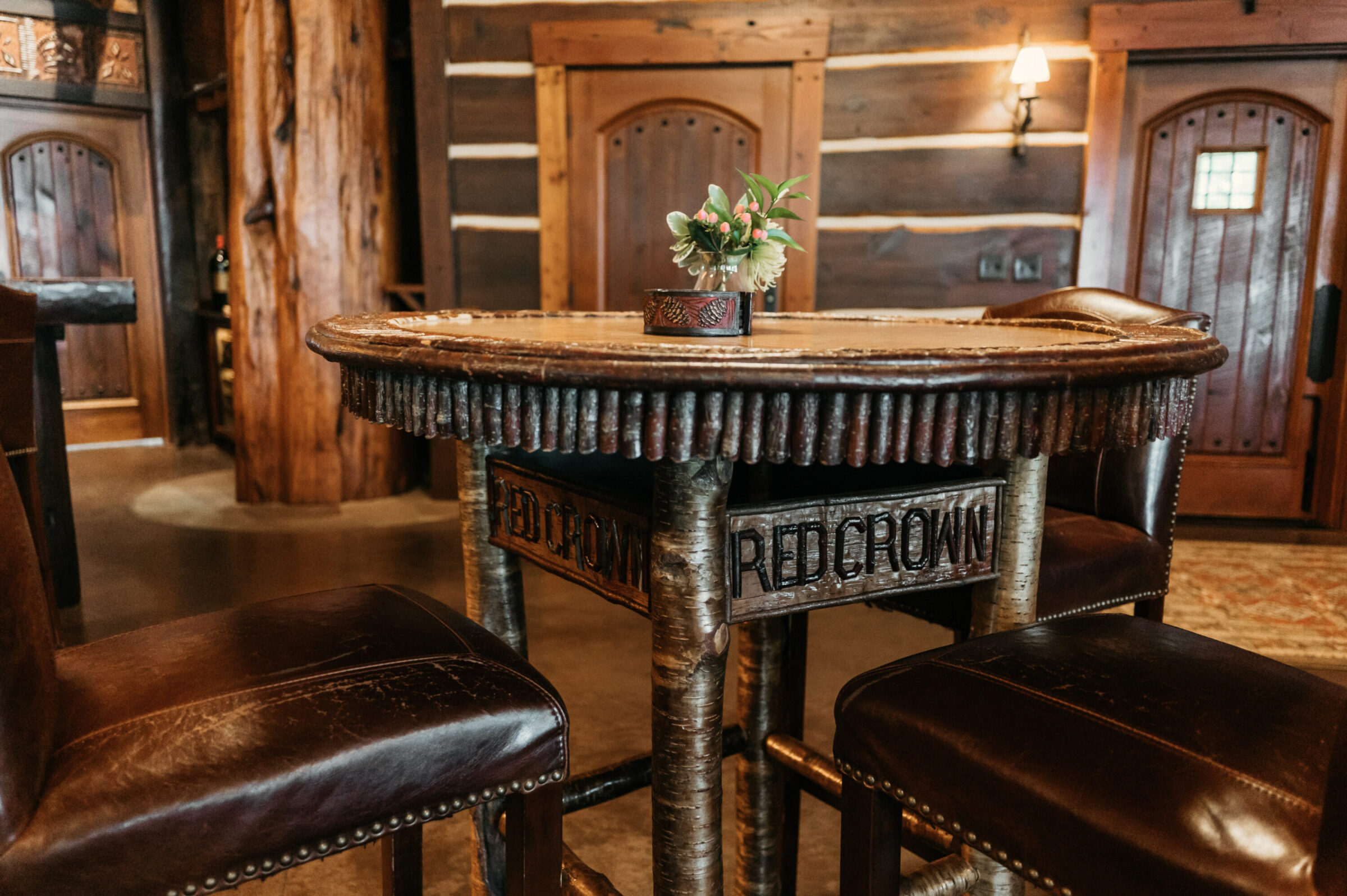 Rustic log table with leather stools and a floral centerpiece.
