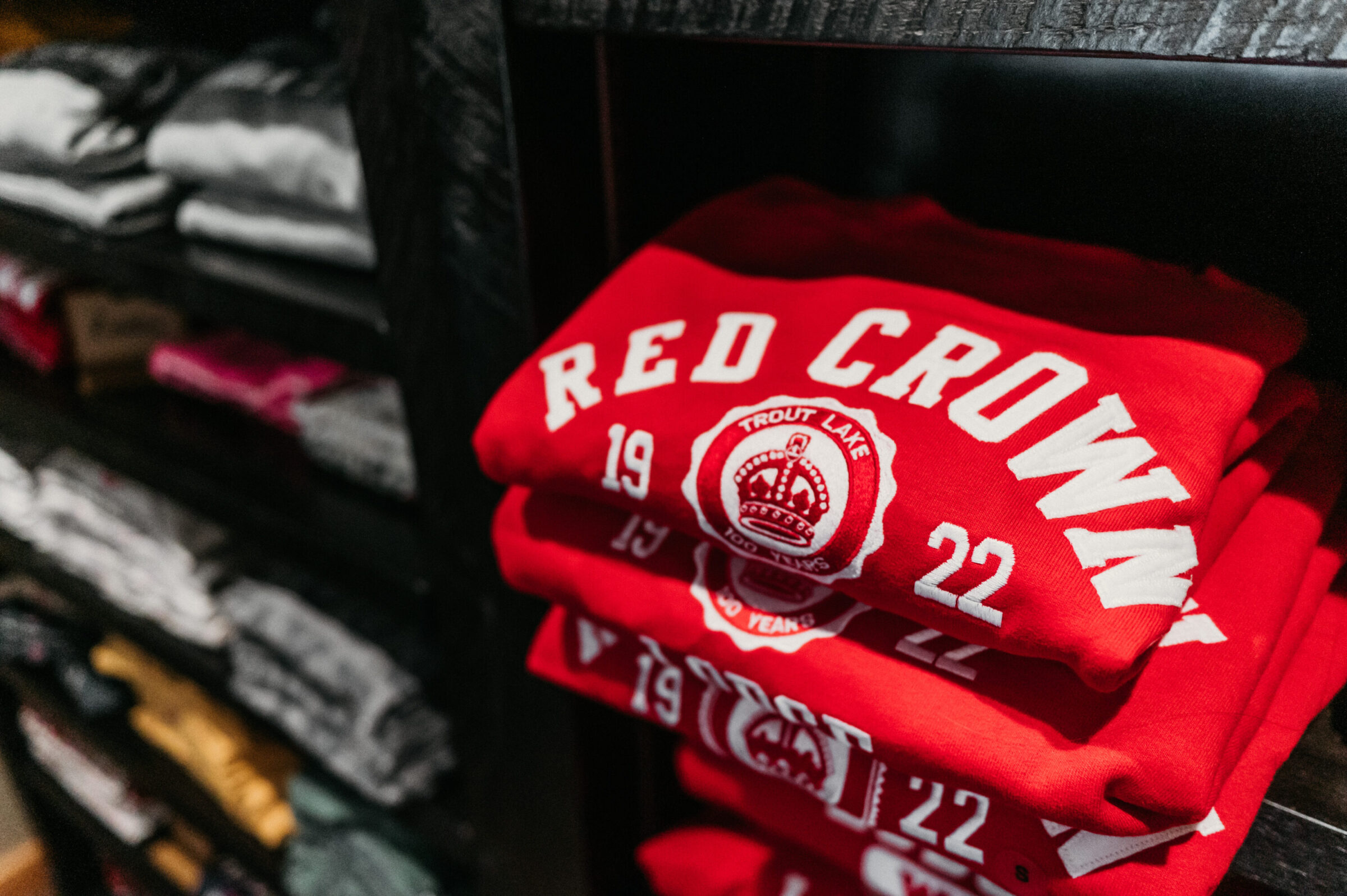 Stack of red "Red Crown Trout Lake" sweatshirts with a crown logo.