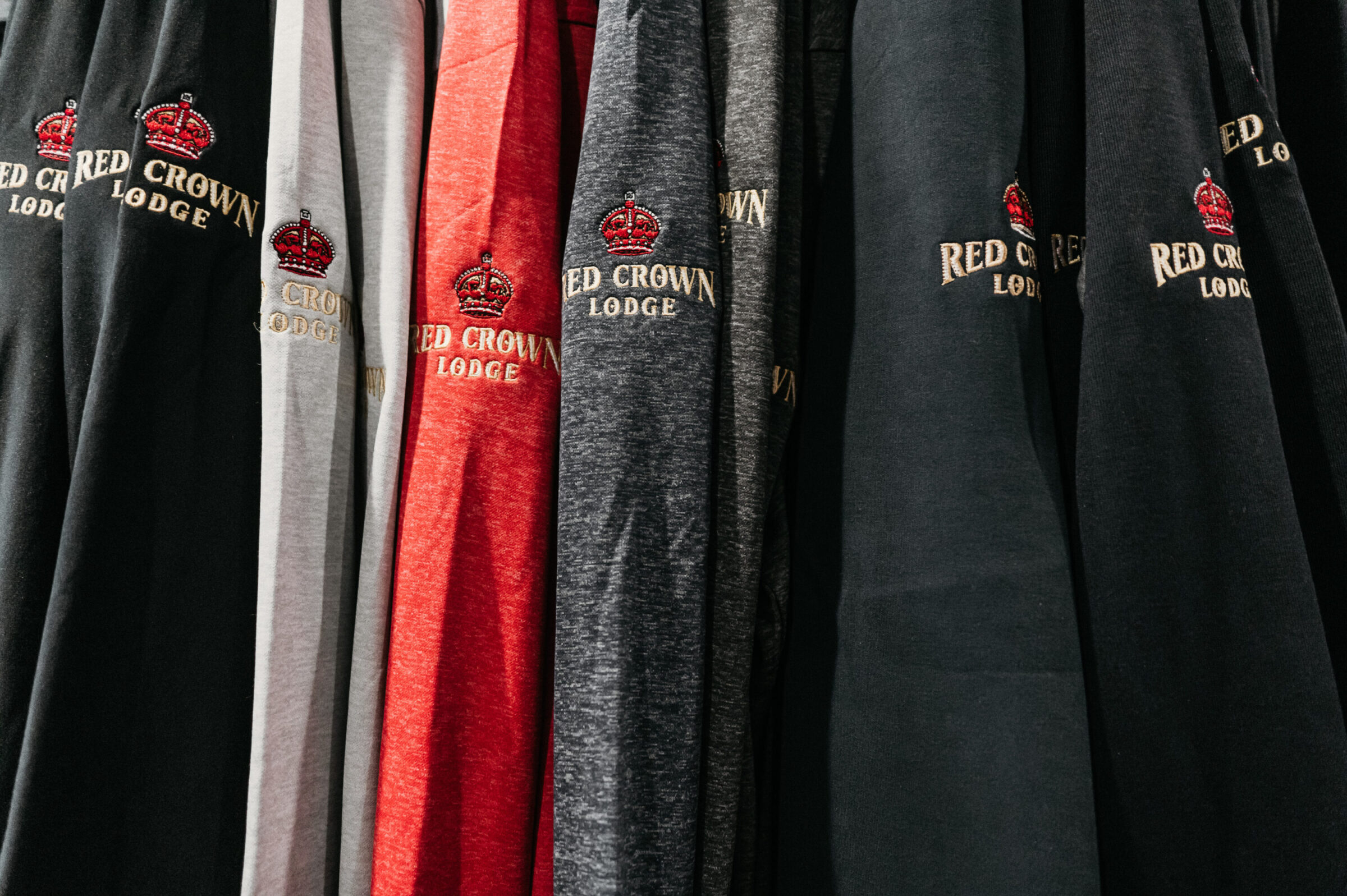 Row of Red Crown Lodge sweatshirts in various colors.