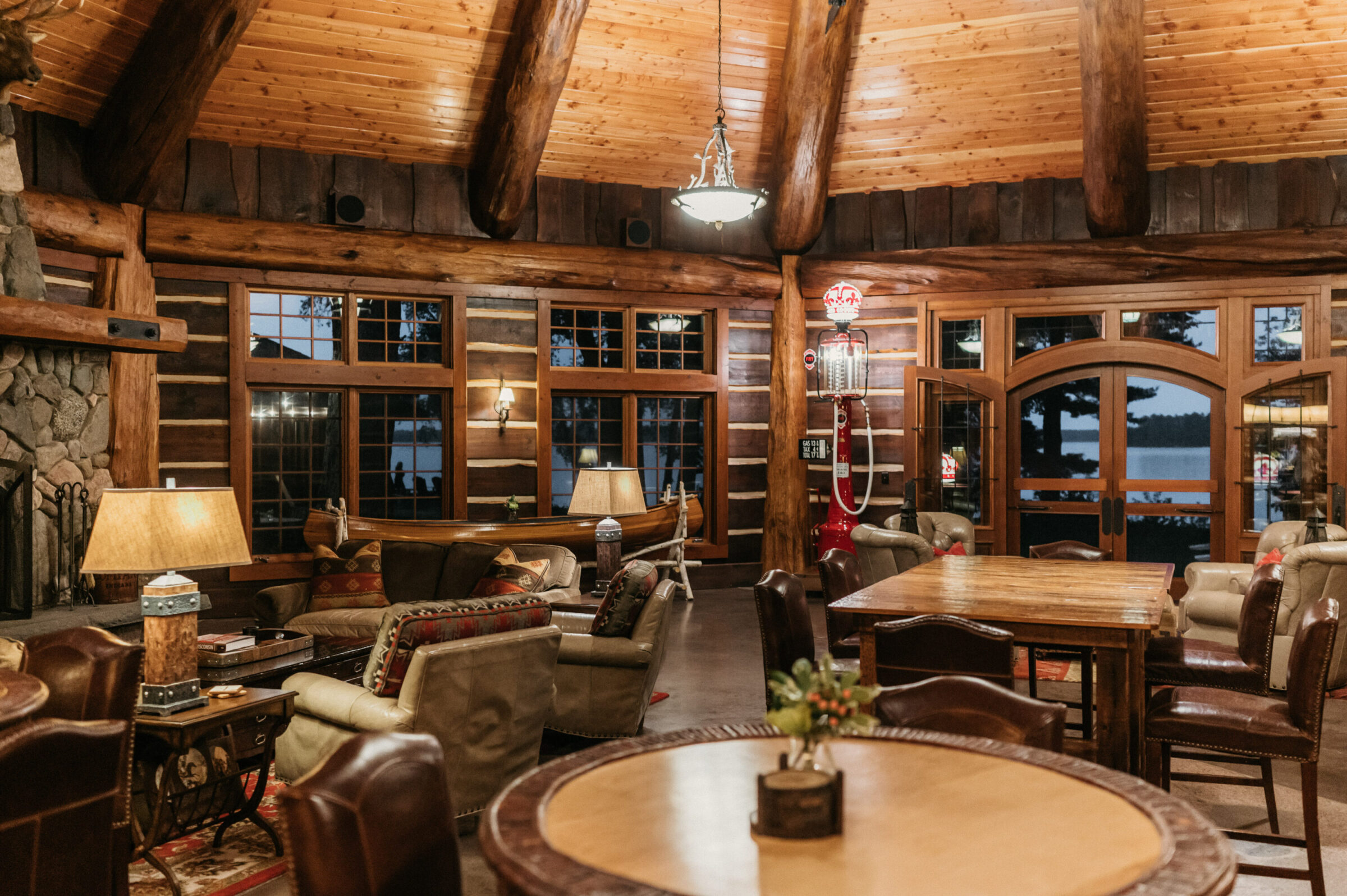 Cozy log cabin living room with fireplace, canoe, and lake view.