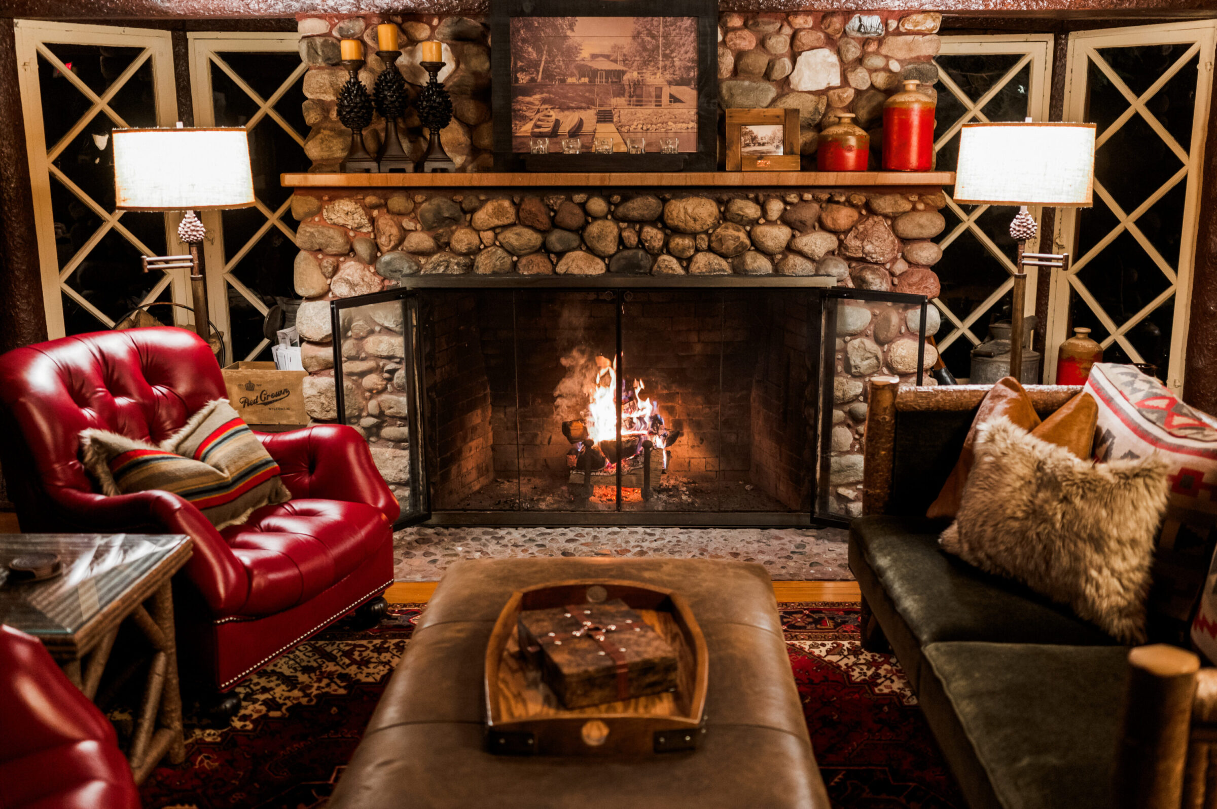 Cozy living room with a roaring fireplace, red armchair, and plush sofa.
