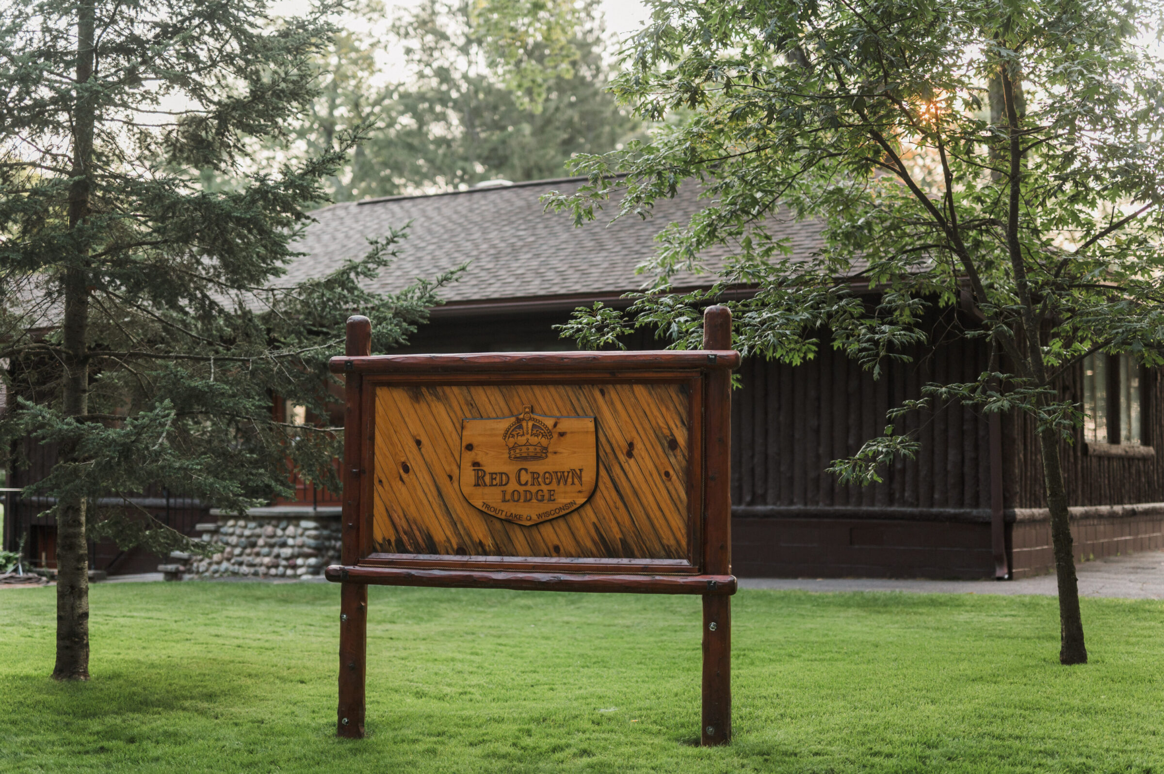 Wooden sign for Red Crown Lodge with a rustic building in the background.
